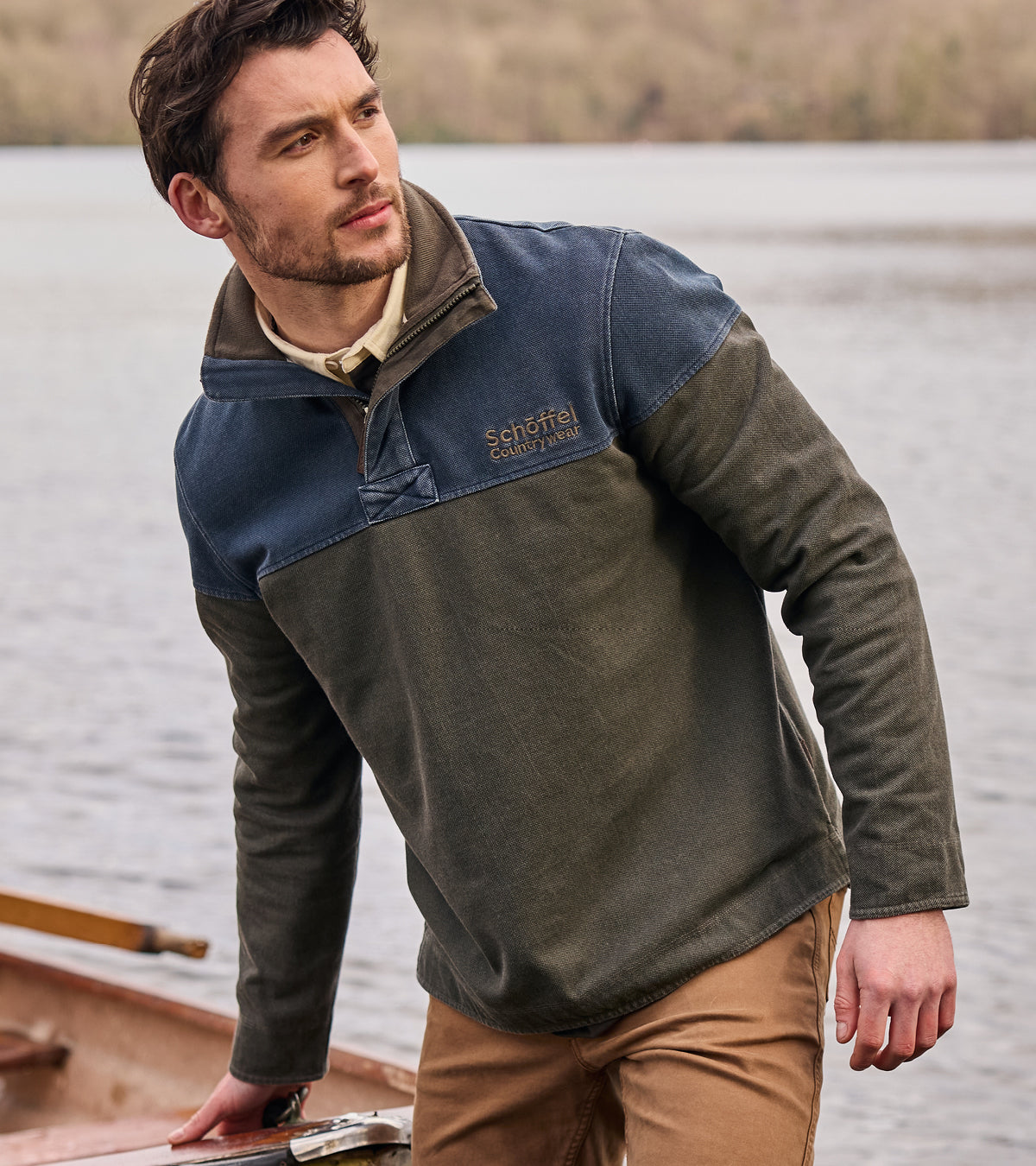 Man wearing a two-tone sweatshirt by a lake