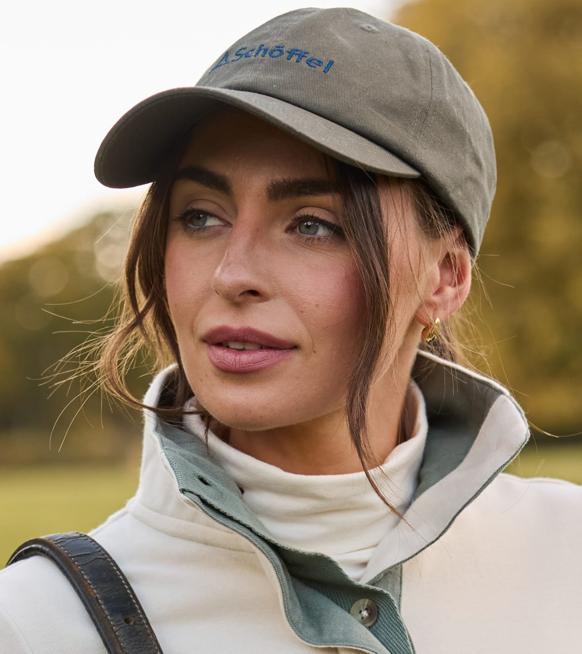 Woman wearing gray-green baseball cap with the blue embroidered brand name 'Schöffel'