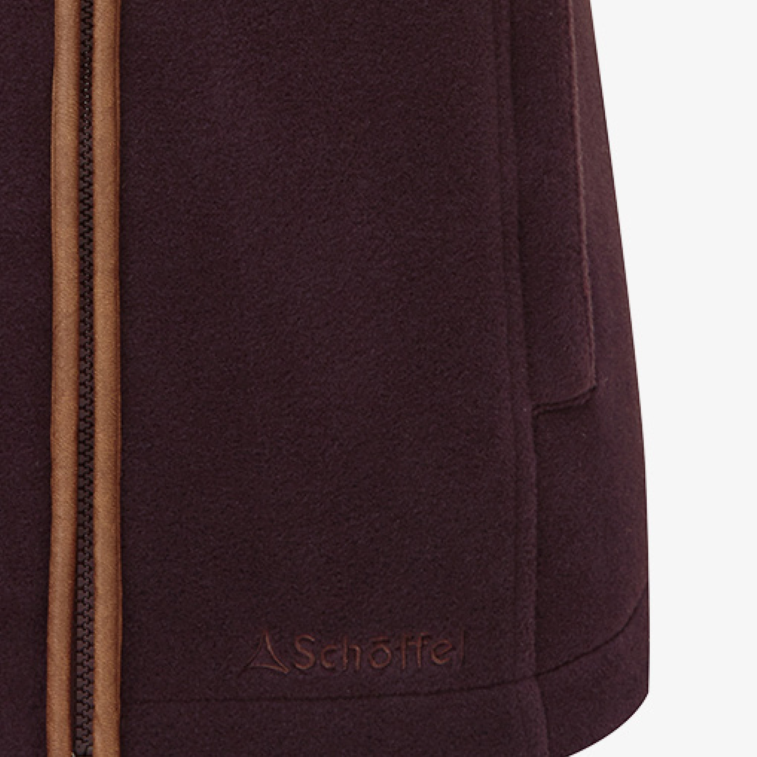 A close up image of a dark plum coloured gilet with contrasting trim. Image highlights the pockets and the Schöffel embroidered logo.
