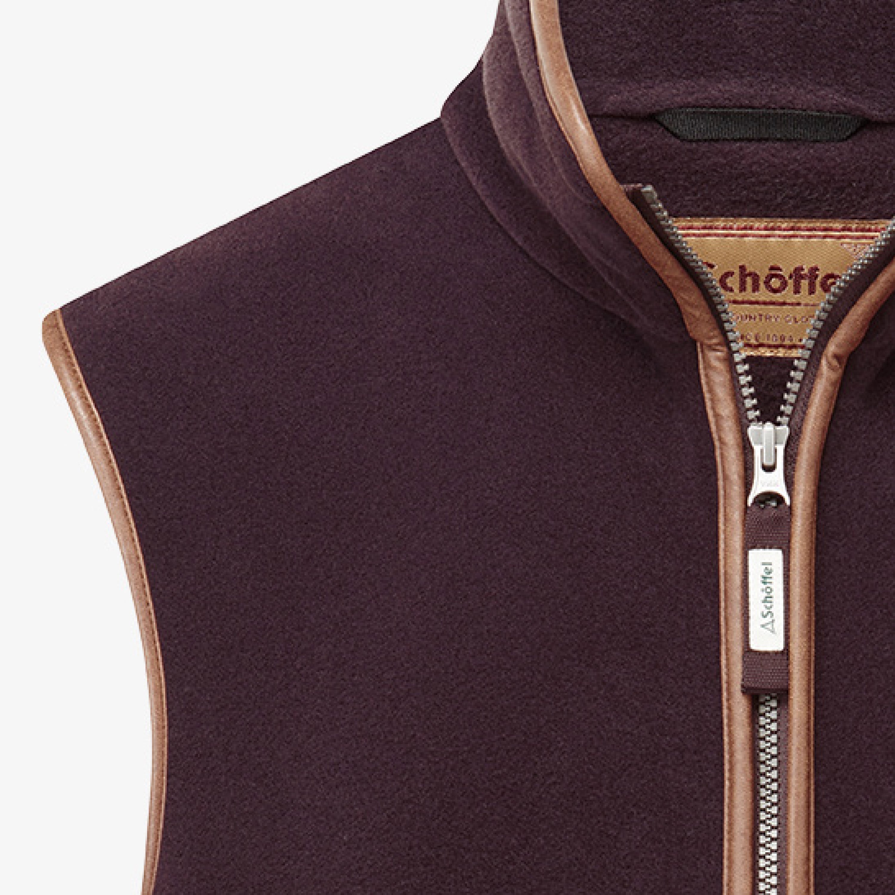 A close up image of a dark plum coloured gilet with contrasting trim. Image highlights the full zip and collar.
