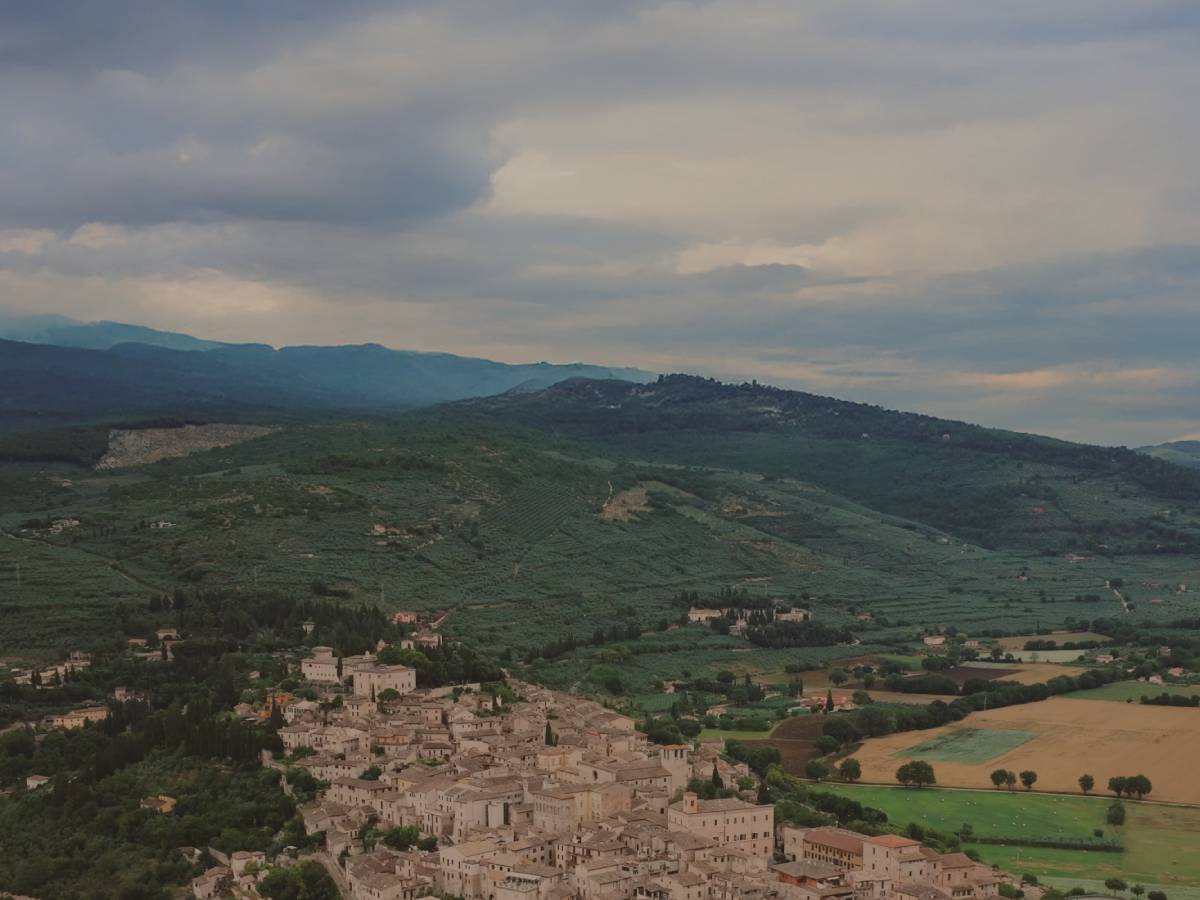 Village nestled in a valley with green hills and a cloudy sky
