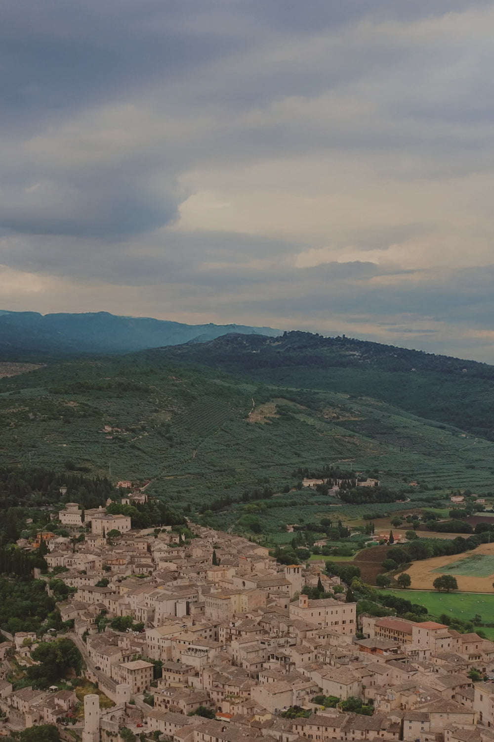 Village nestled in a valley with rolling hills and a cloudy sky