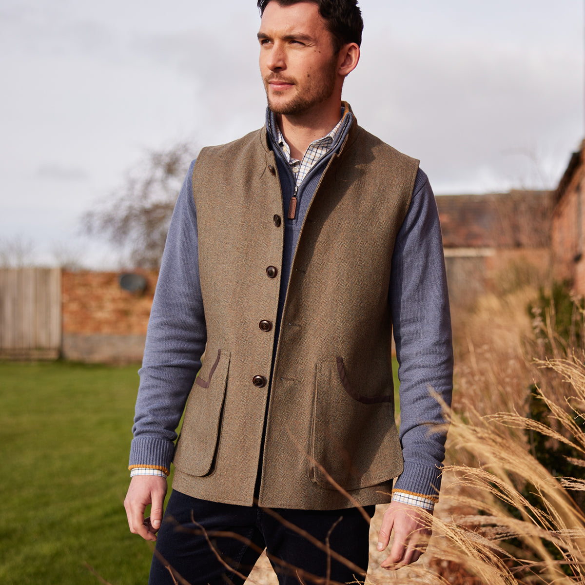 Man wearing a brown vest over a blue shirt in an outdoor setting