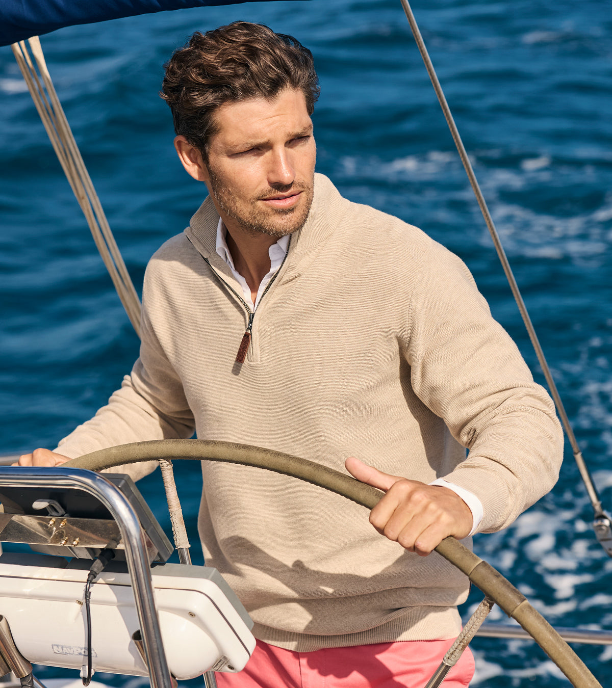 Man steering a sailboat on a clear day