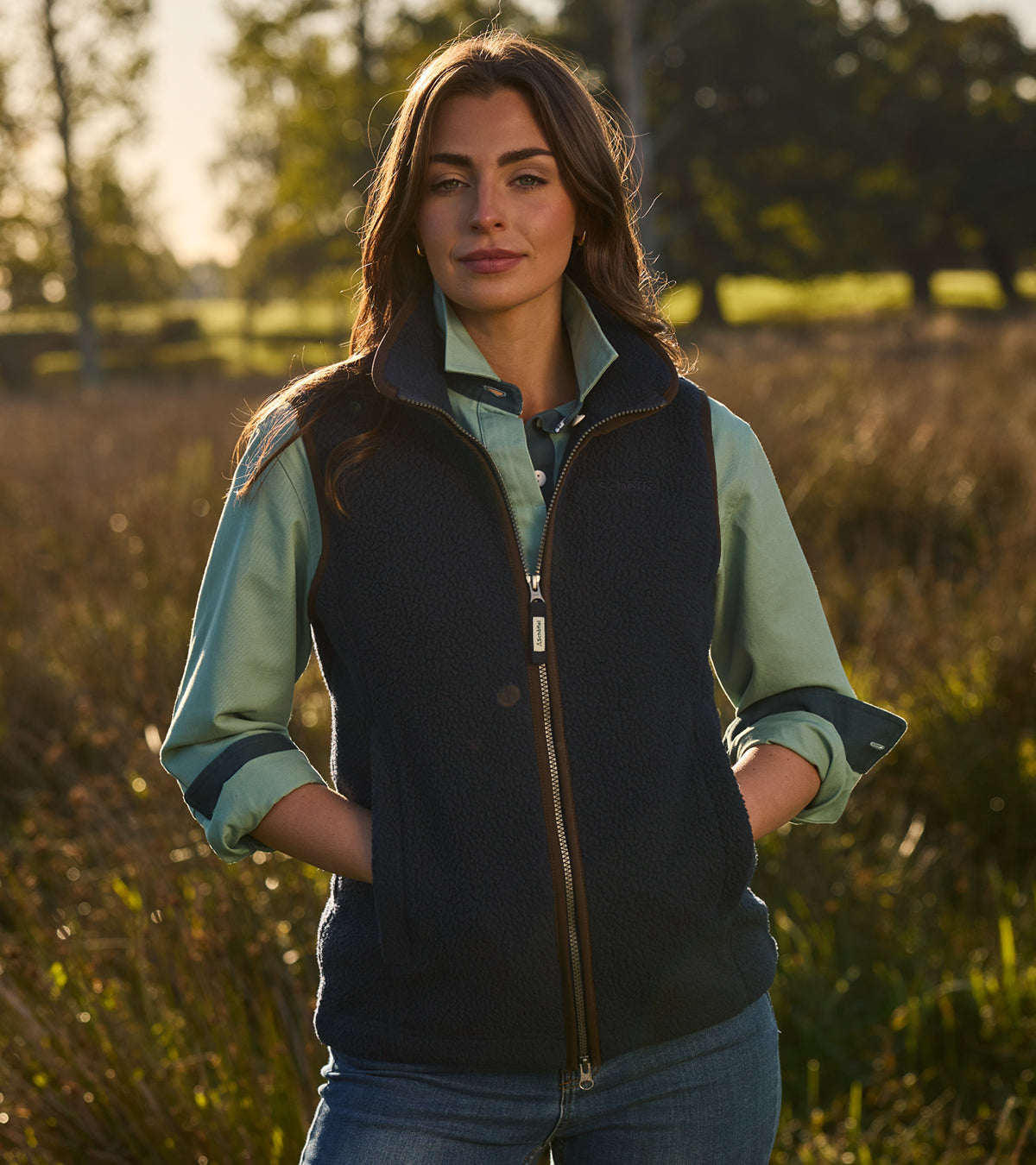Woman wearing a black vest over a light blue shirt in a field
