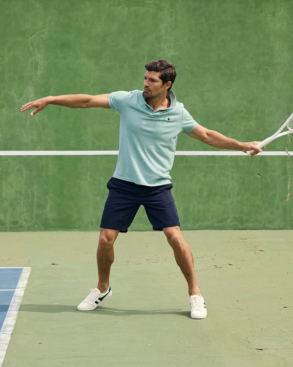 Man playing tennis on a green court