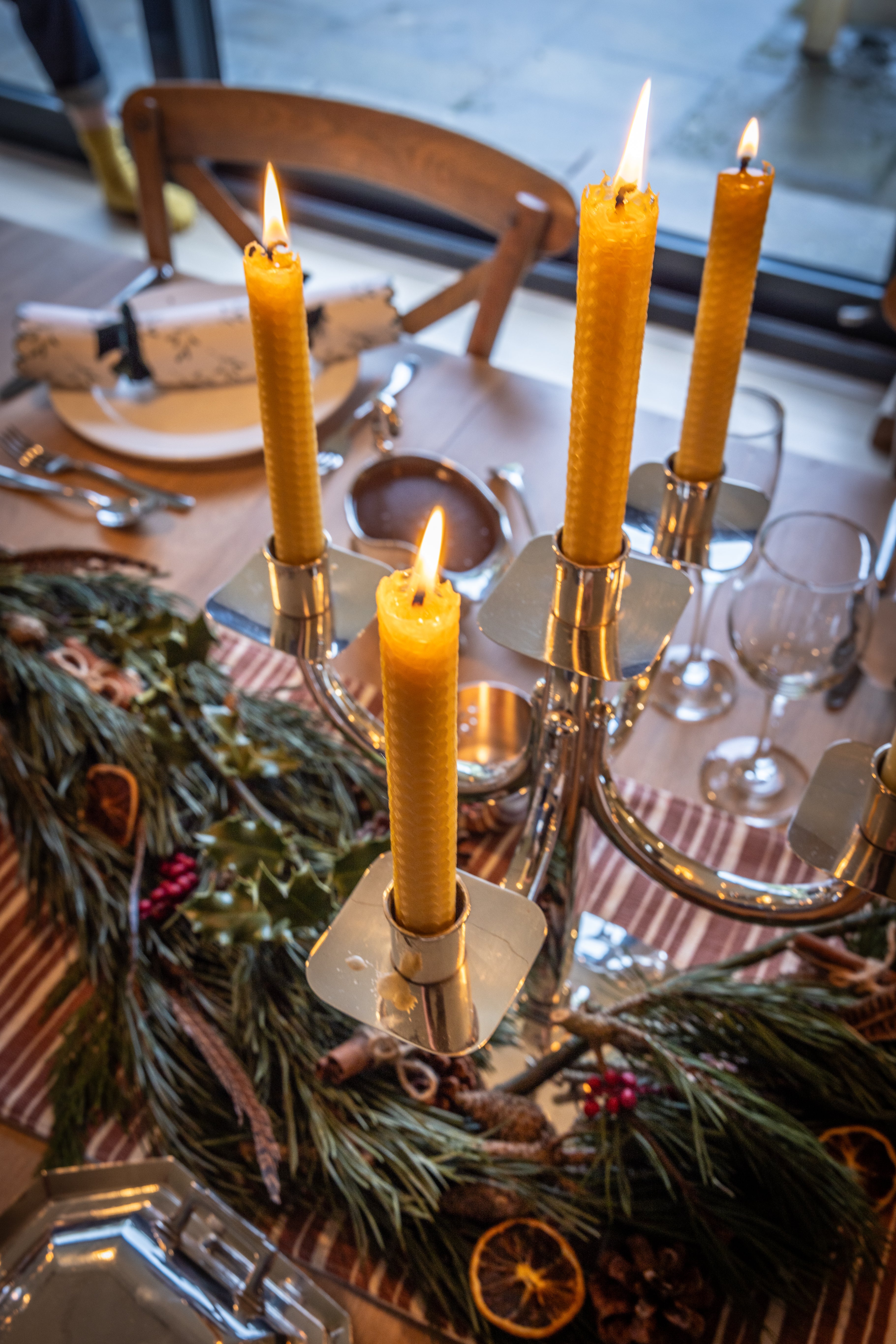 Close up of a festive table set with tall dinner candles in the centre.