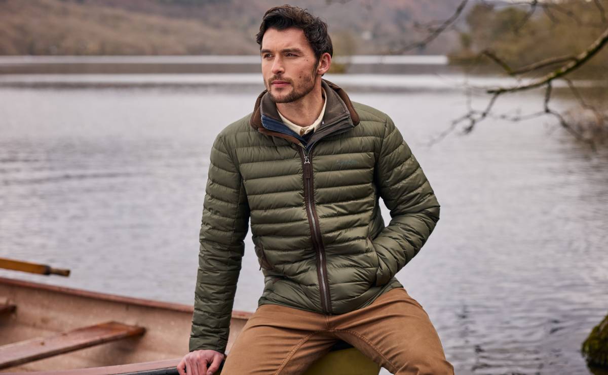 Man wearing a green jacket by a lake