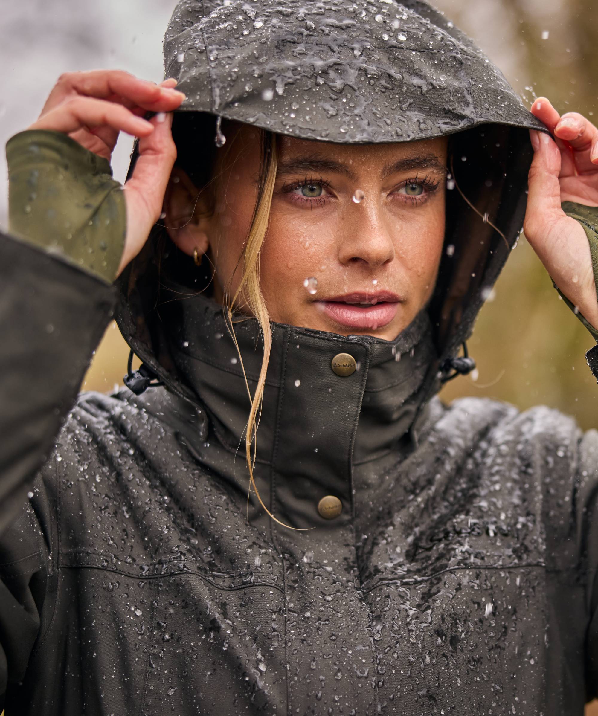 Person wearing a raincoat in a rainy outdoor setting