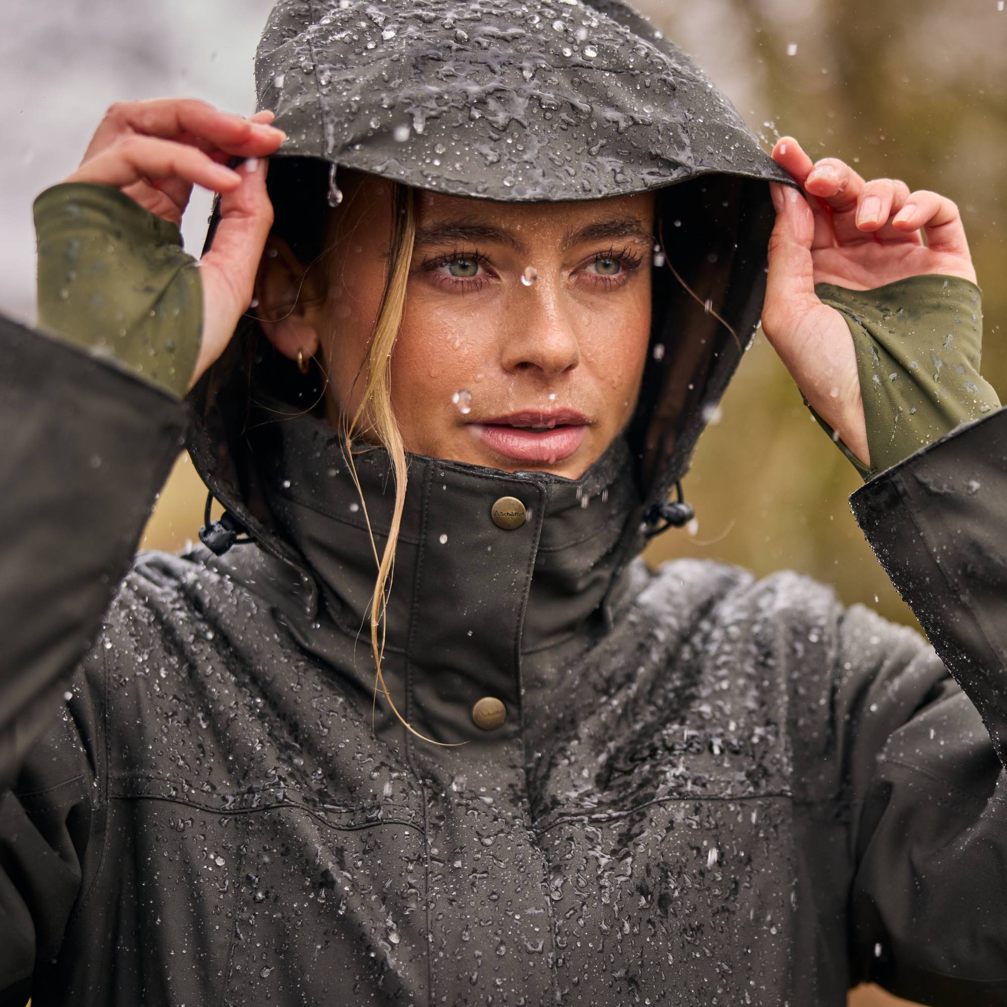 Person wearing a raincoat with a hood in a rainy outdoor setting