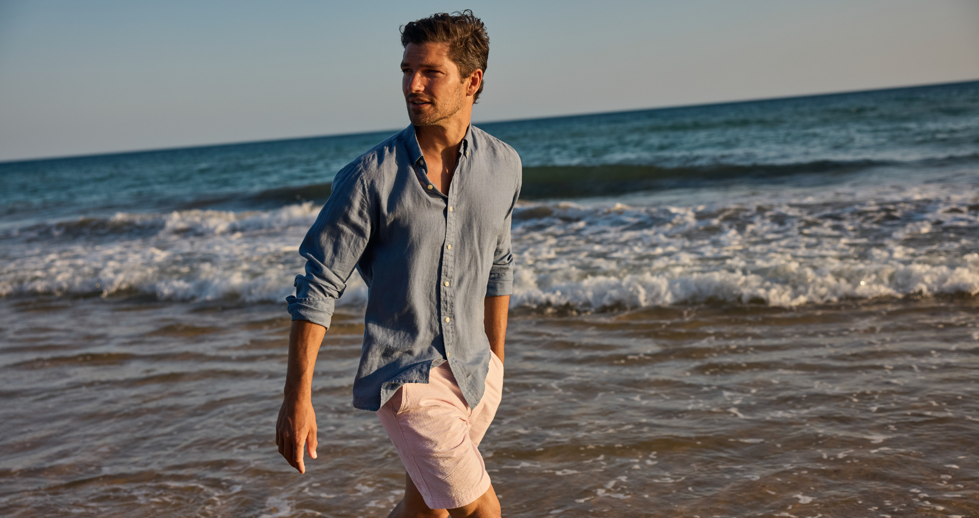 Man walking on a beach with ocean waves in the background