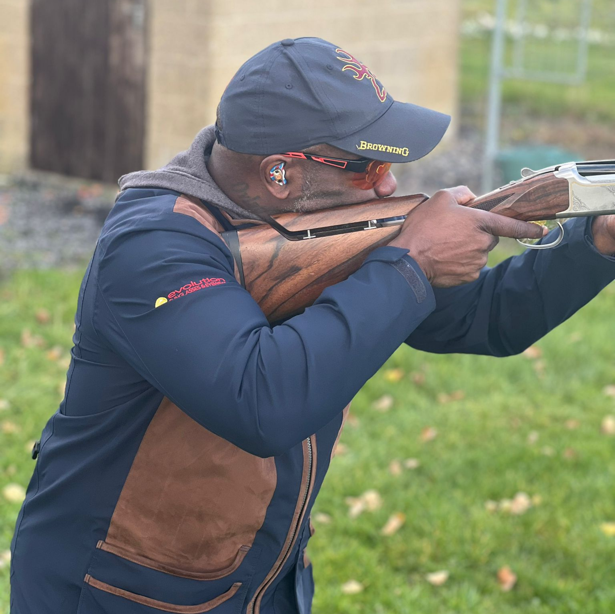Man in shooting attire holding a shotgun outdoors