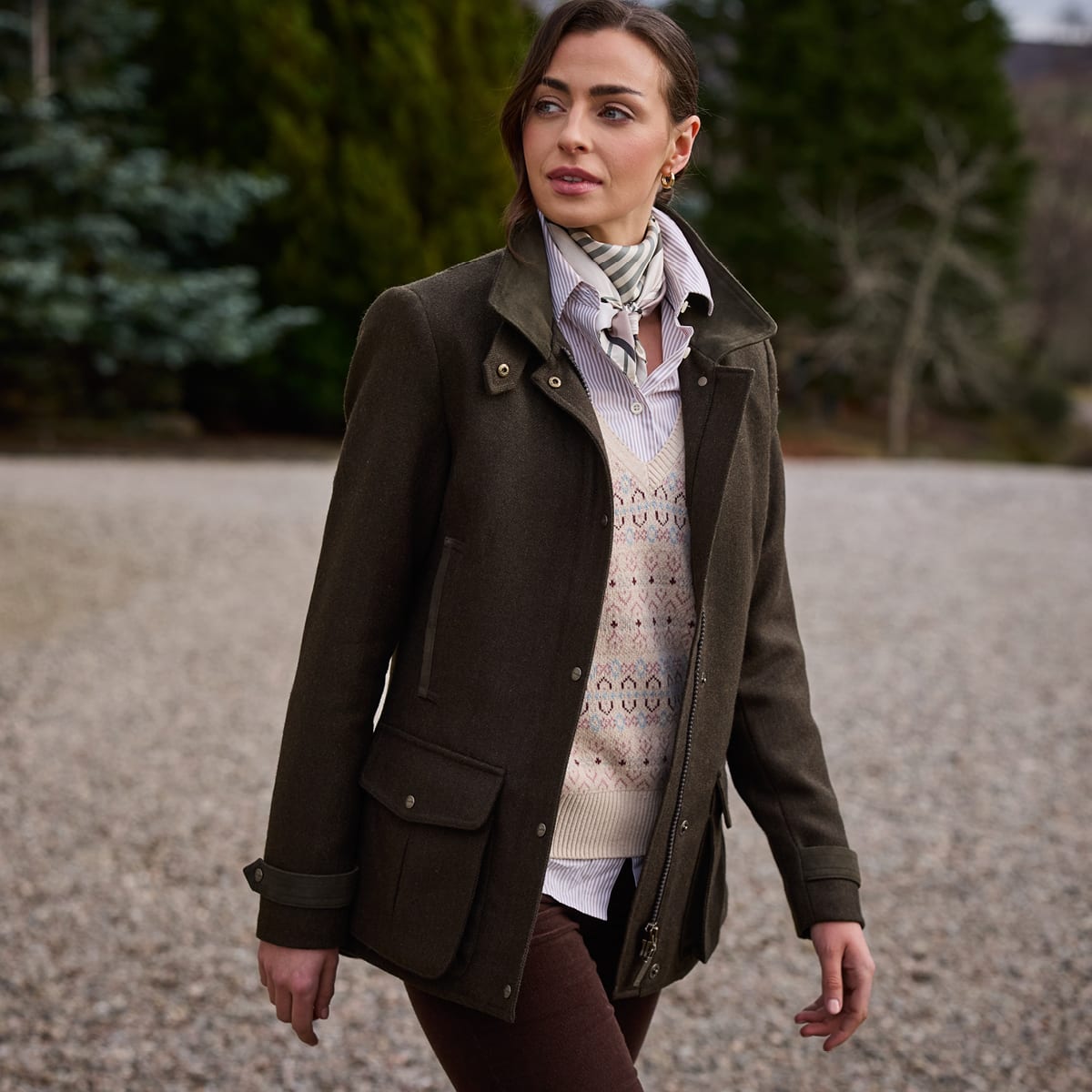 Woman wearing dark olive green wool-blend coat over a cream knit sweater and scarf