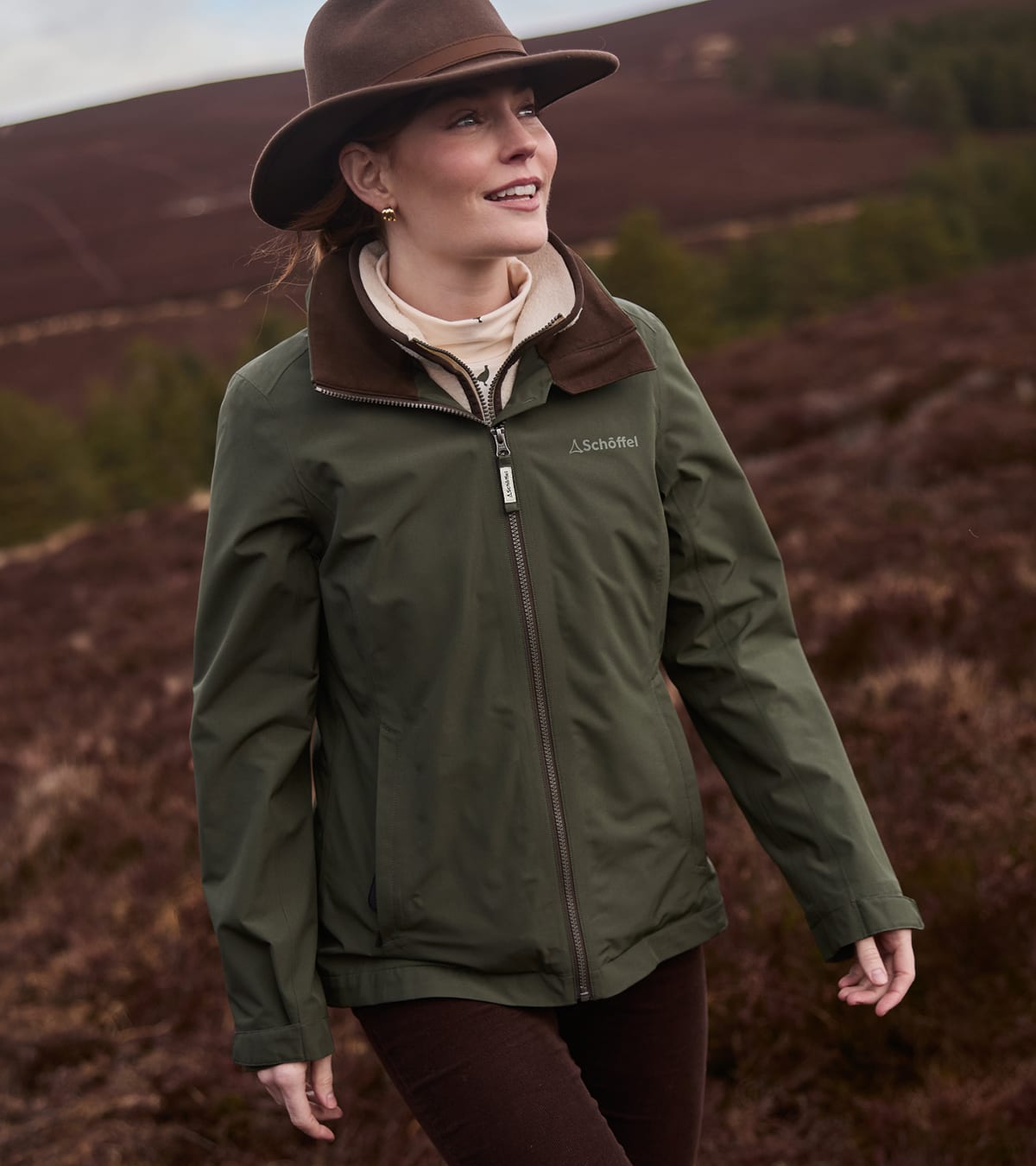 Woman wearing olive green waterproof jacket with brown corduroy collar and cream fleece
