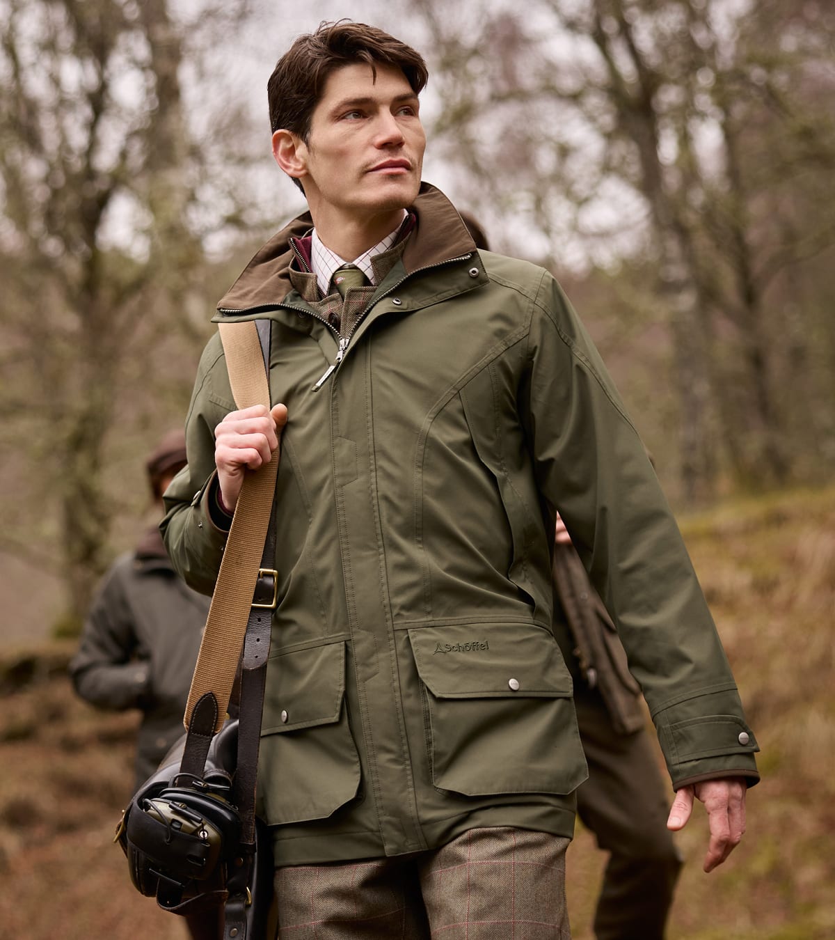 Man standing in woodland wearing a green shooting jacket