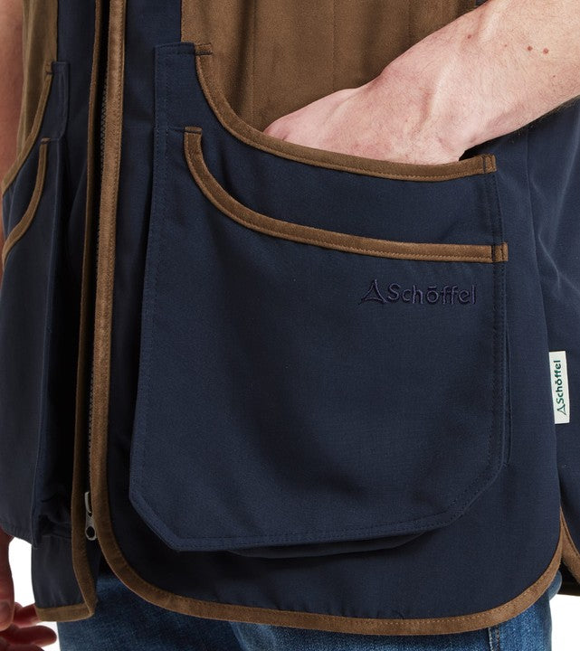 Detail of Schöffel Men's Grimsthorpe Clay Shooting Vest in navy, showing the large double bellows cartridge pocket with suede trim and embroidered Schöffel branding