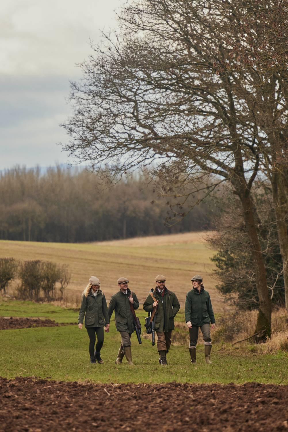A group of people walking in a field wearing countrywear.