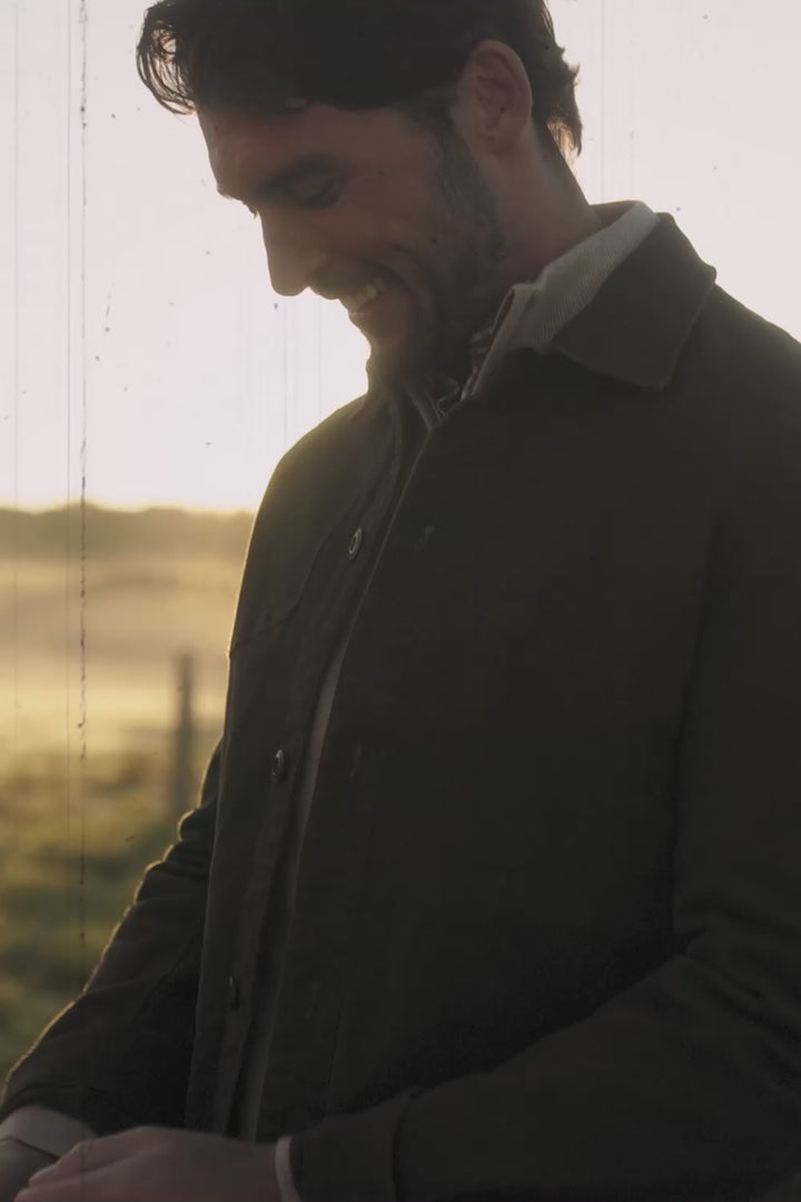 Two people wearing green jackets outdoors with natural backgrounds