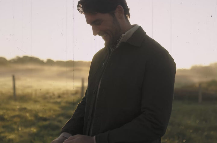 Two people wearing green jackets outdoors with natural backgrounds