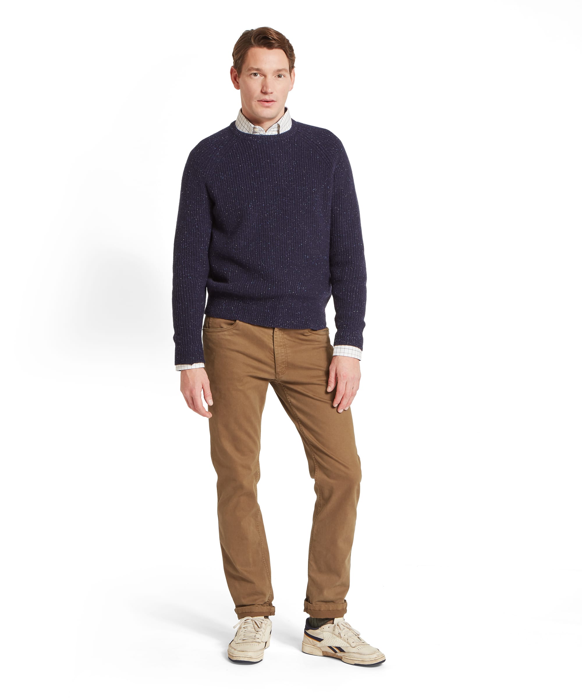 Schöffel Men's Balmaha Crew Neck Jumper in Blue - front view of a relaxed-fit navy donegal ribbed lambswool crew neck jumper with raglan sleeves, layered over a check shirt and worn with khaki trousers.