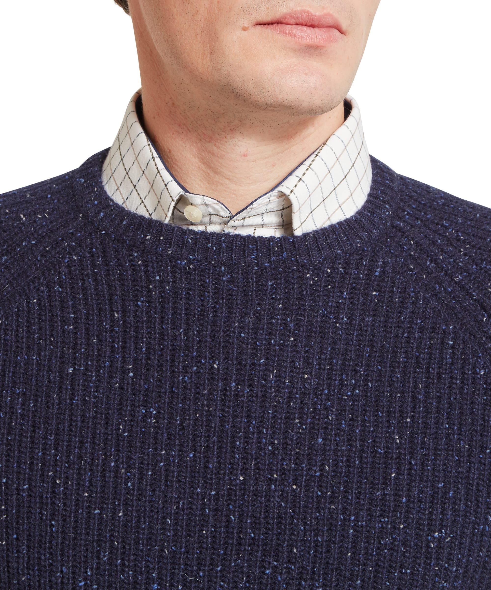 Schöffel Men's Balmaha Crew Neck Jumper in Blue - side profile view highlighting the chunky ribbed construction and relaxed fit of the navy donegal lambswool crew neck, layered over a check shirt and khaki trousers.