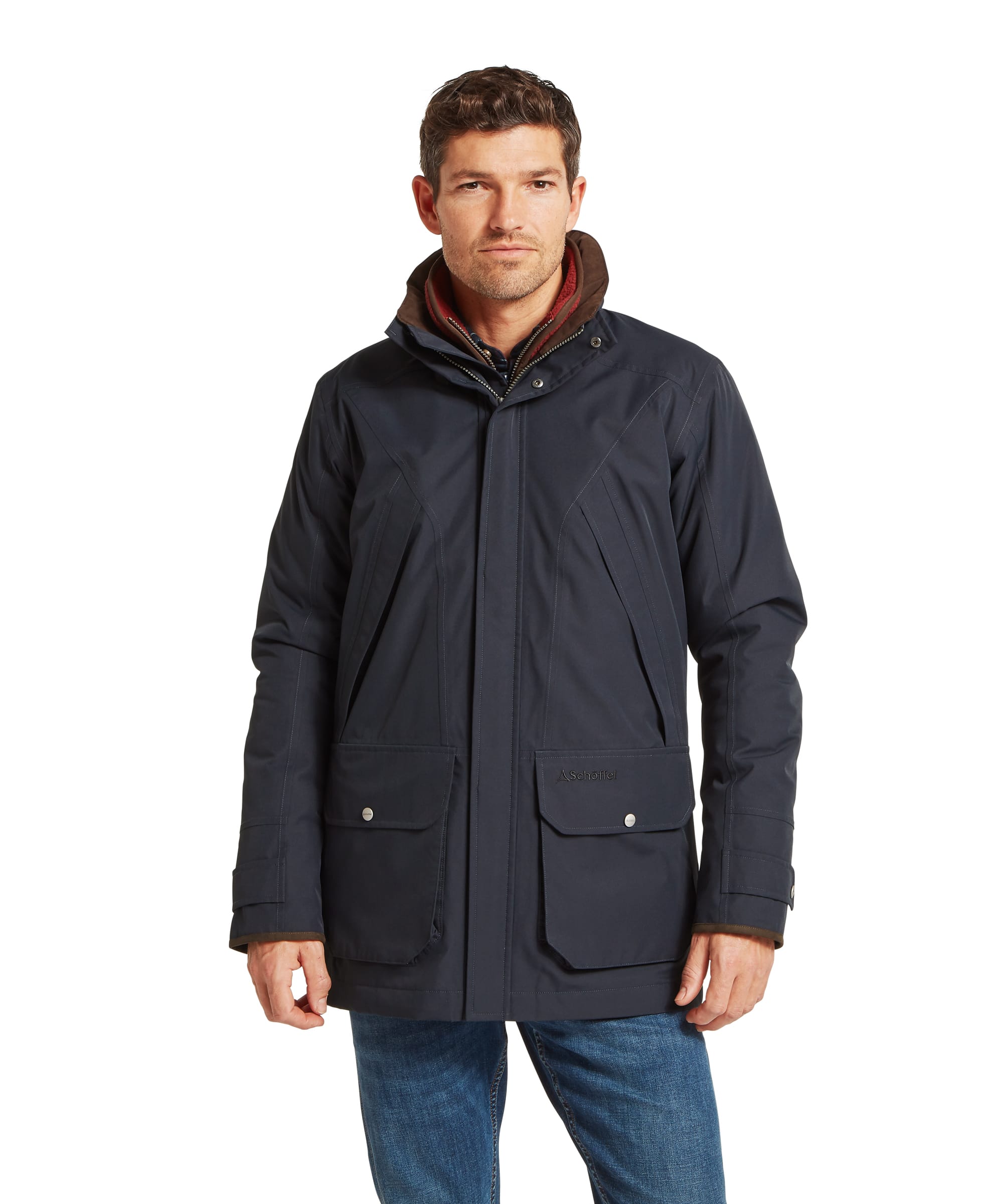 Schöffel Men's Barrow Country Coat in Navy - front view of a smart waterproof navy country coat with a funnel collar, concealed zip fastening, large press-stud flap pockets, and subtle quilted shoulder panels, worn with jeans and Chelsea boots.