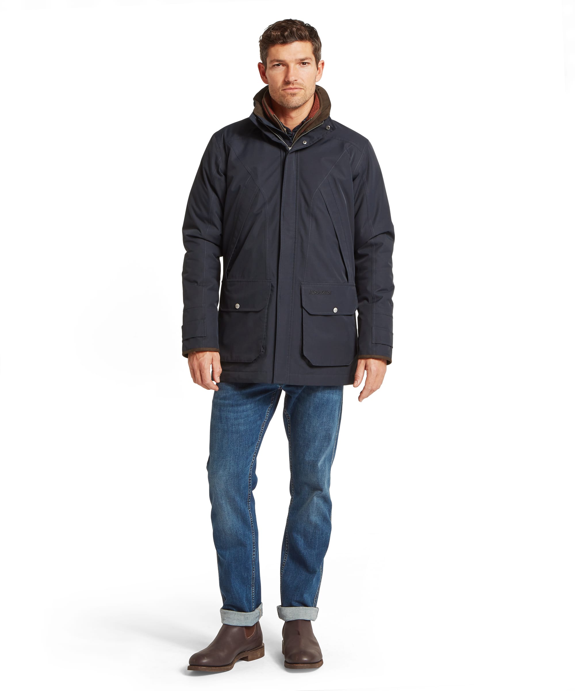 Schöffel Men's Barrow Country Coat in Navy - full-length front view showing the mid-length silhouette, large flap pockets, and layered collar system with fleece and wax cotton inner visible, worn with jeans and Chelsea boots.