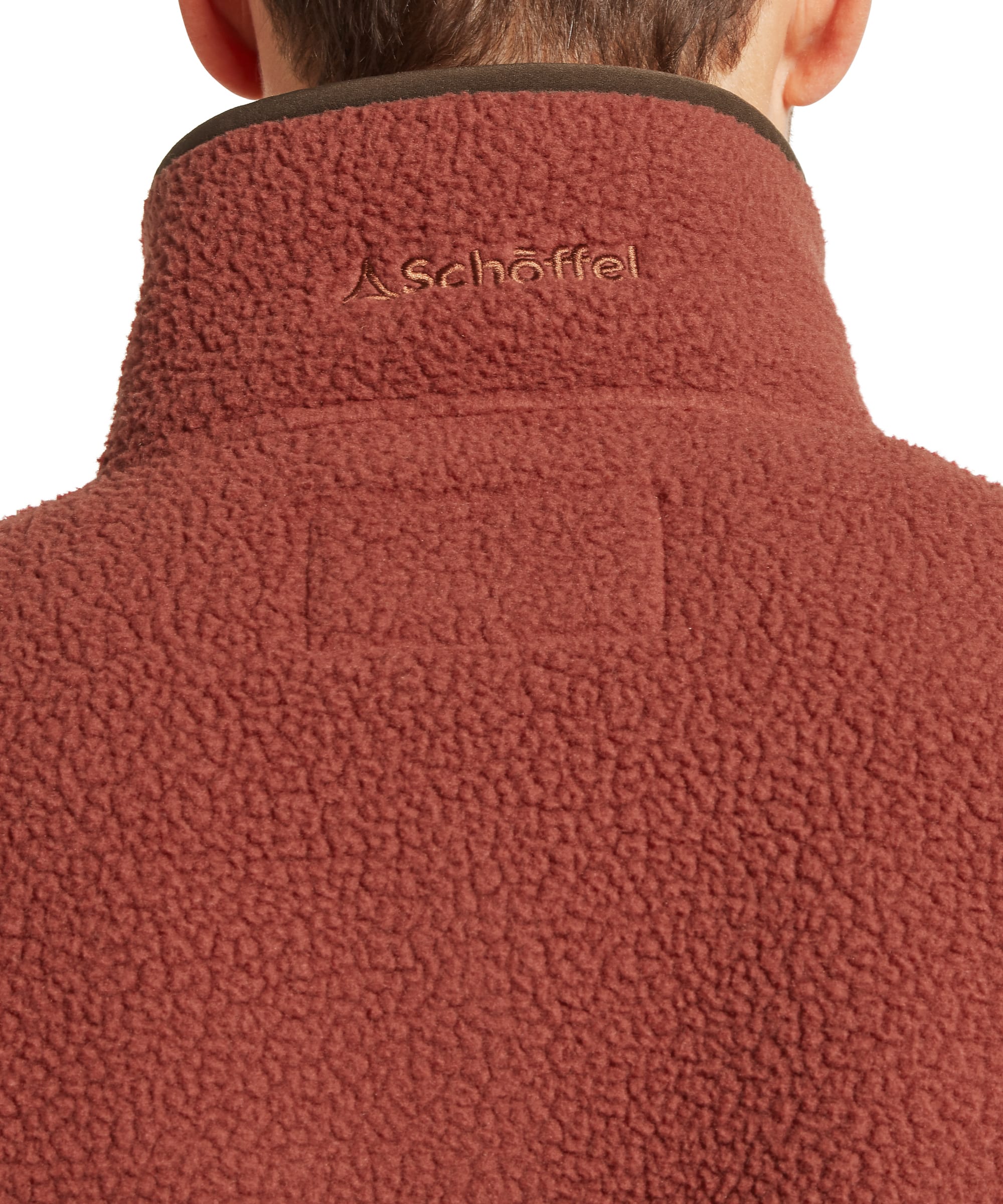 Close-up back collar detail of the Schöffel Men's Berkeley Retro Fleece in Brown, showing the Schöffel embroidered logo on the rust sherpa fleece funnel neck with dark brown contrast trim and a pass-through loop.