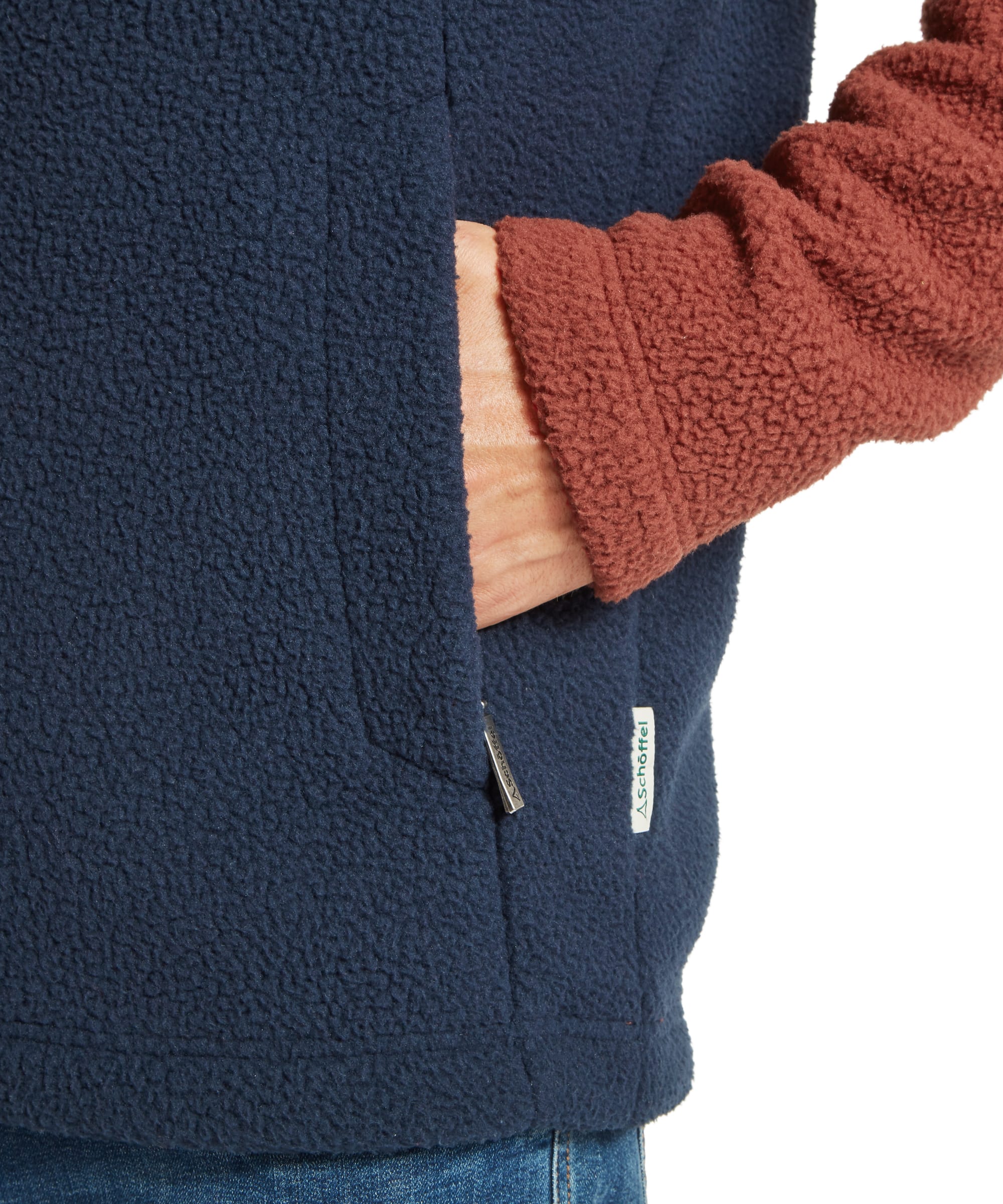 Close-up pocket detail of the Schöffel Men's Berkeley Retro Fleece in Brown, showing the navy sherpa kangaroo pocket with Schöffel woven badge, contrast rust sherpa sleeve, and the colour-block panelling of the retro fleece.