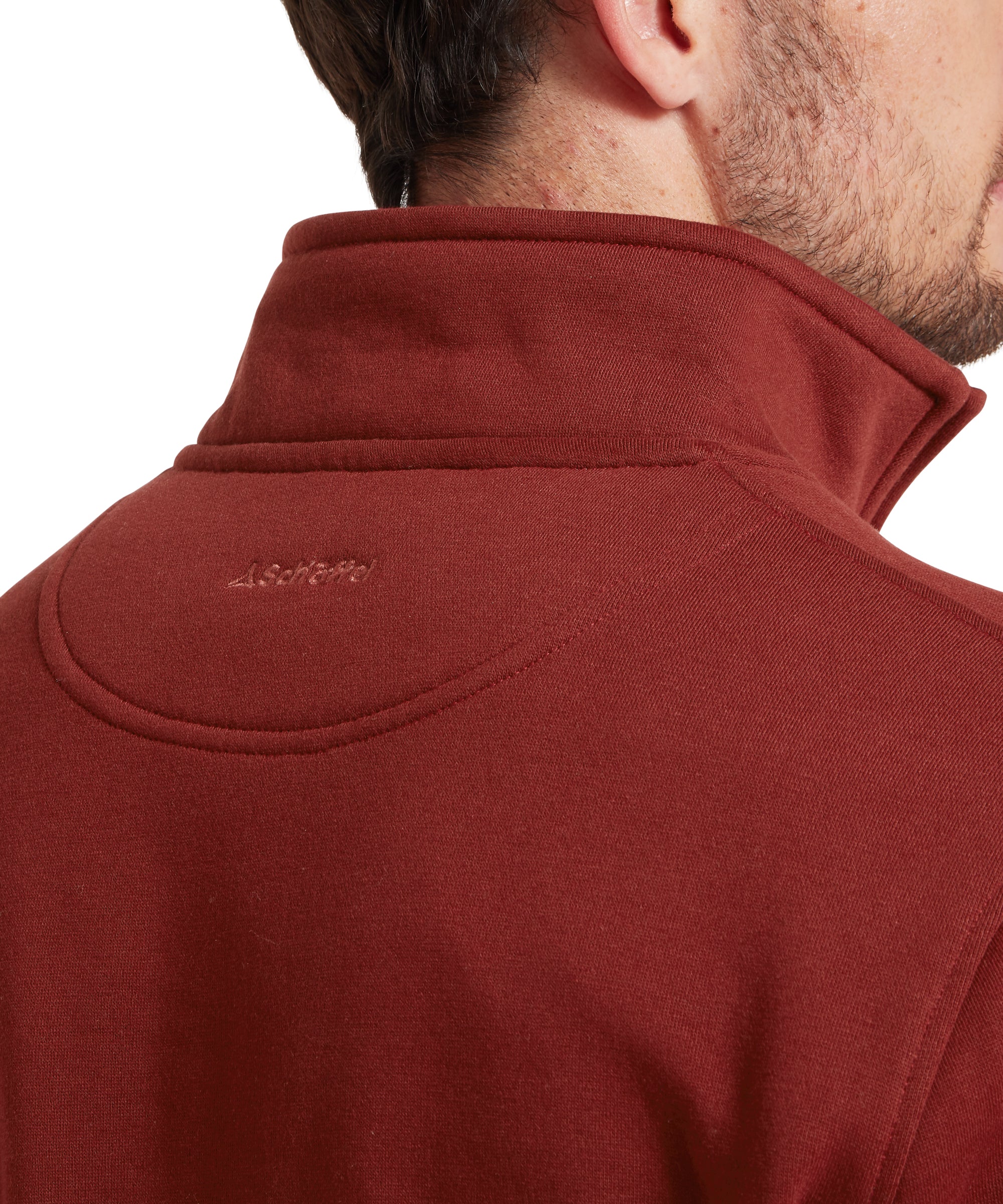 Close-up of a red sweatshirt with a brand logo on the collar against a white background