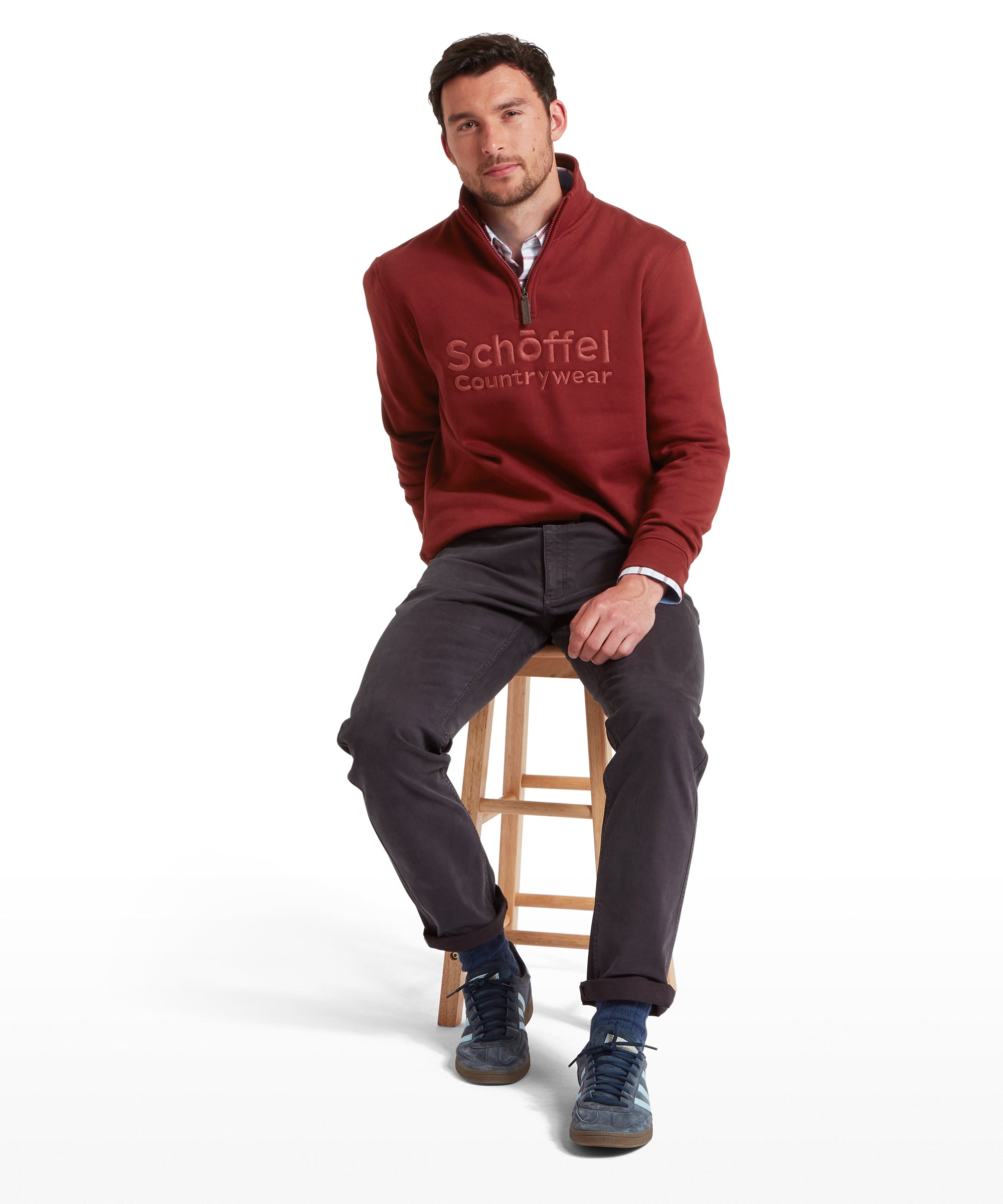 Man wearing a red Schöffel Country Wear sweater sitting on a stool against a white background