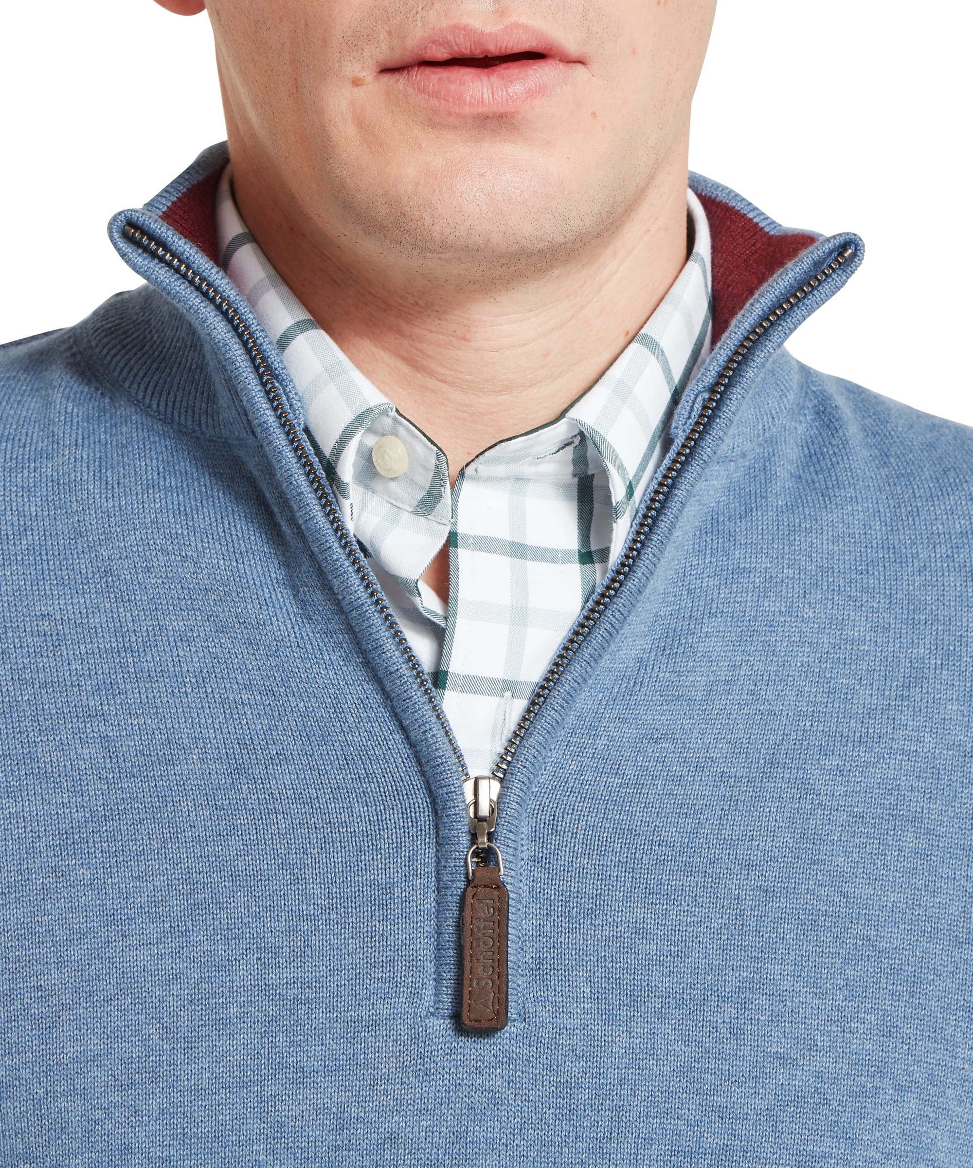 Close-up collar and zip detail of the Schöffel Men's Calton Cotton Cashmere Quarter Zip Jumper in Blue, showing the open funnel neck, quarter-zip with antiqued brass teeth, Schöffel leather zip pull, and check shirt collar layered beneath.