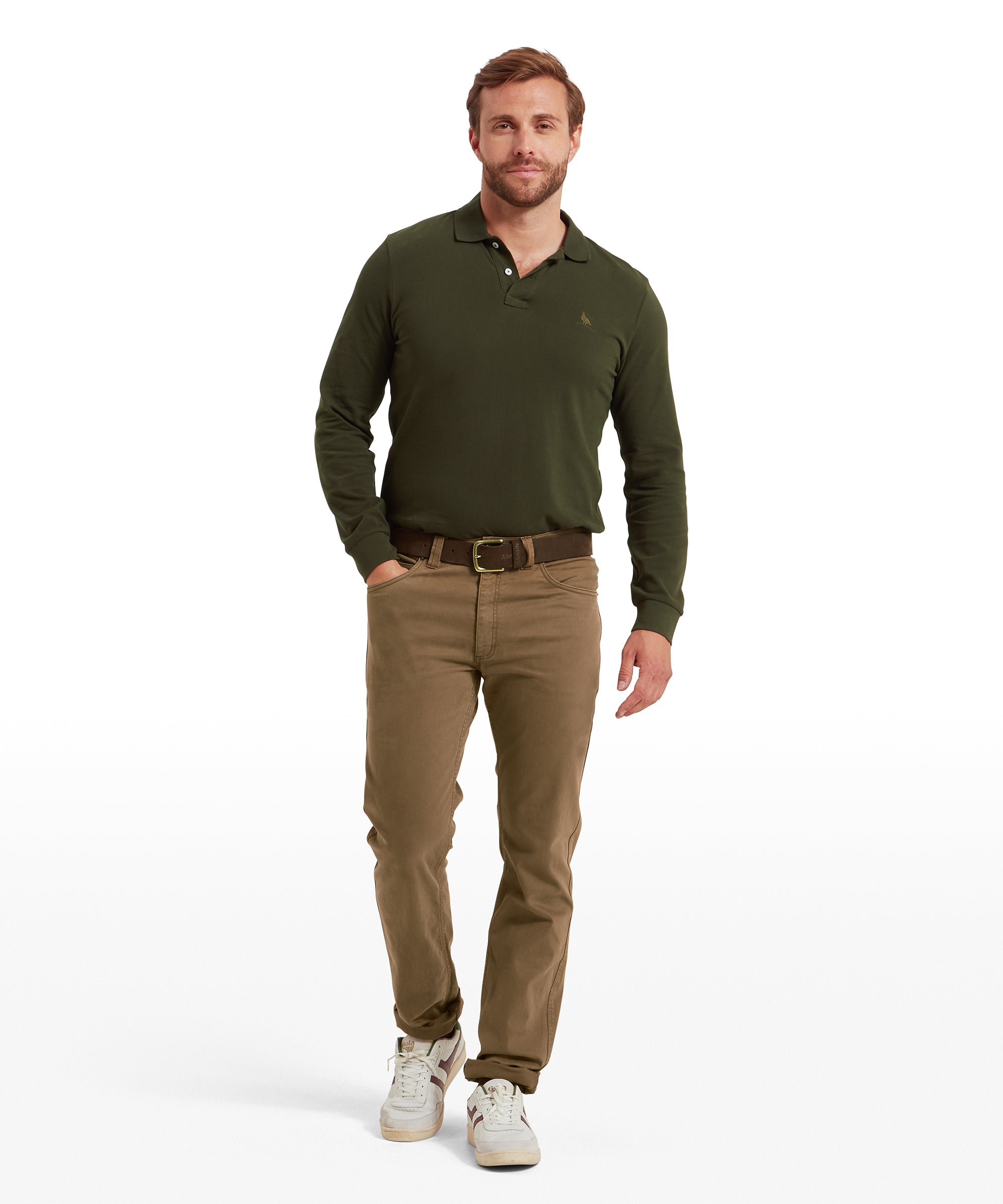 Man wearing a green polo shirt and brown jeans against  a white background
