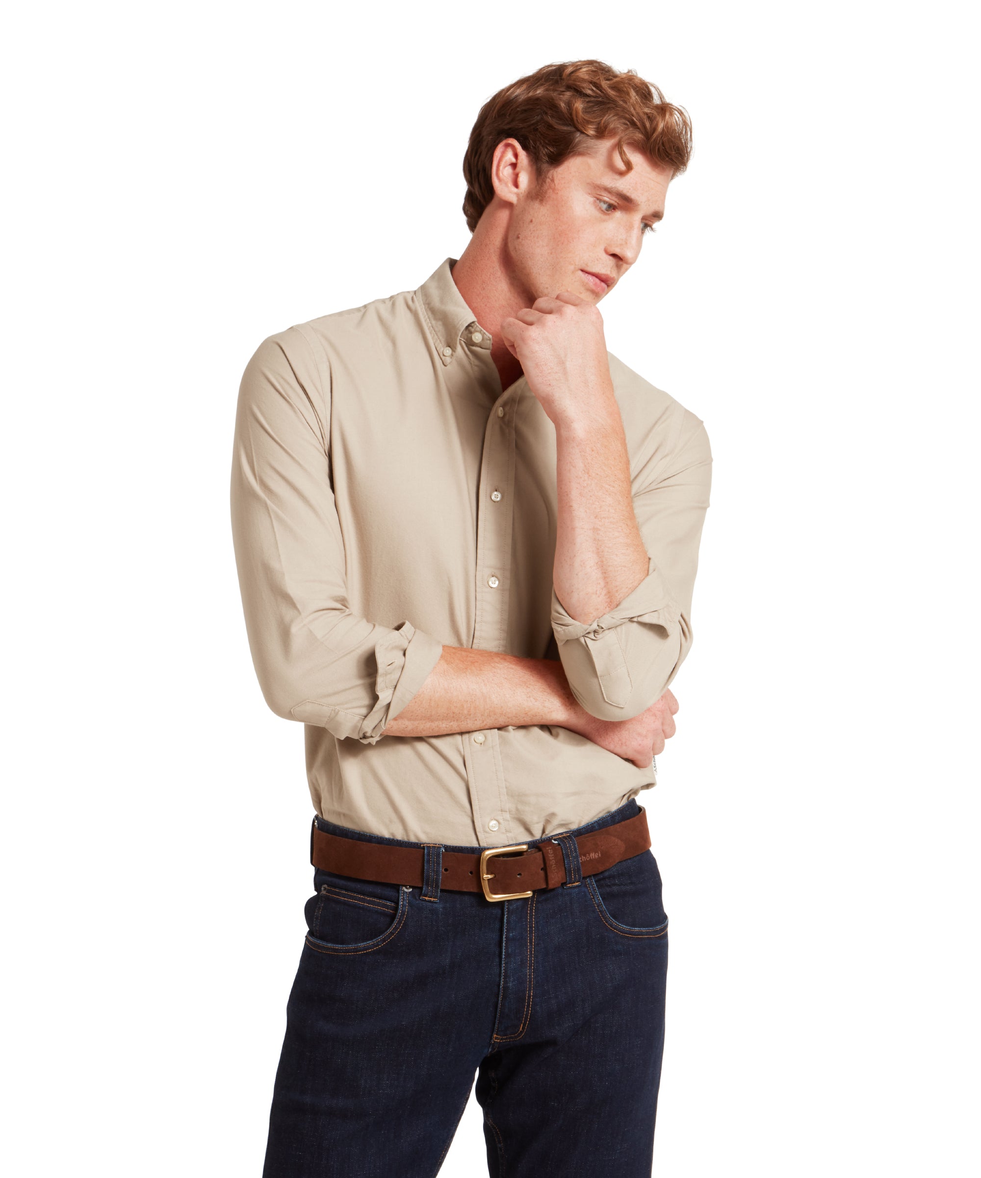 Man wearing a beige shirt and dark jeans on a white background
