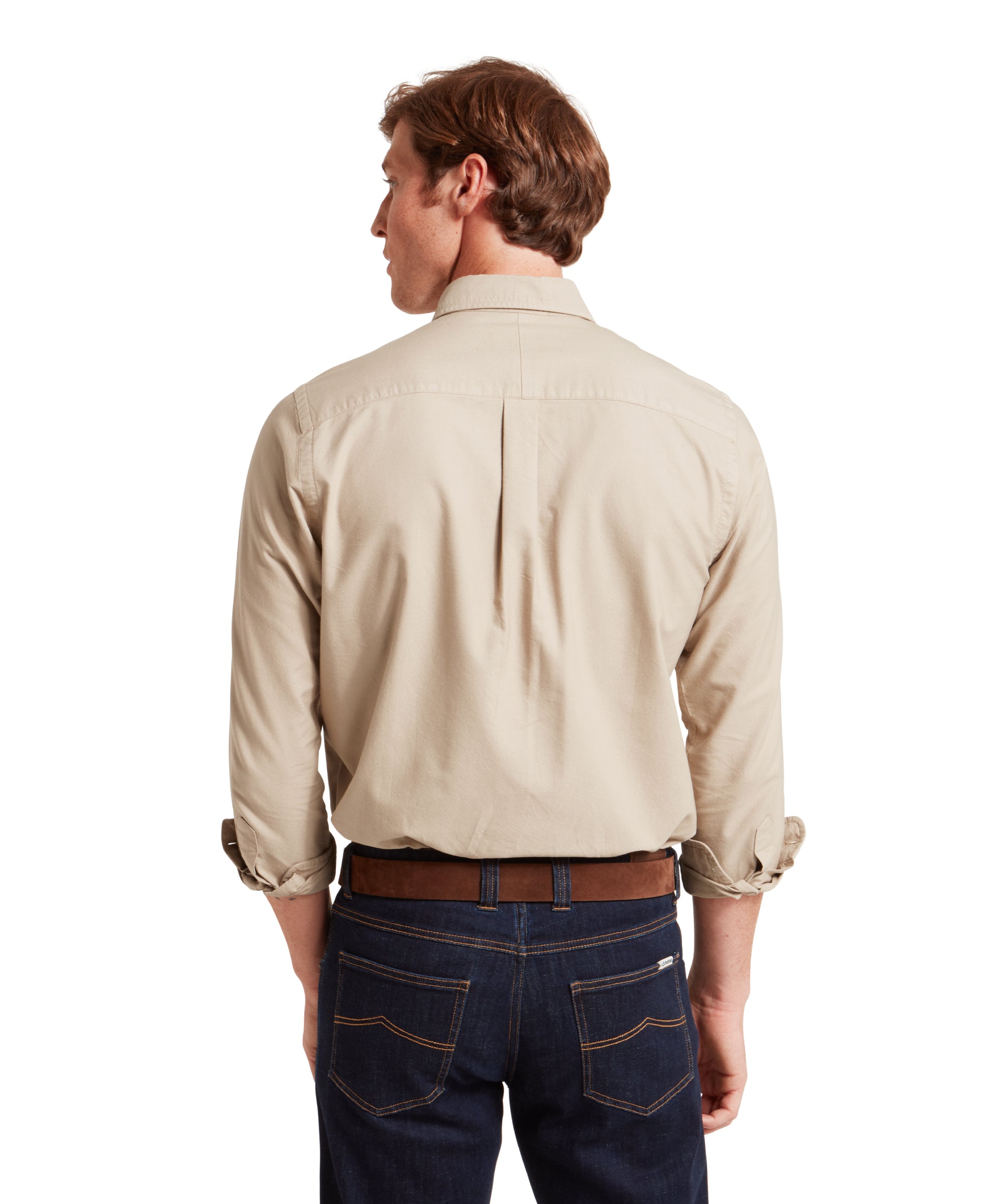 Man wearing a beige shirt and dark jeans on a white background