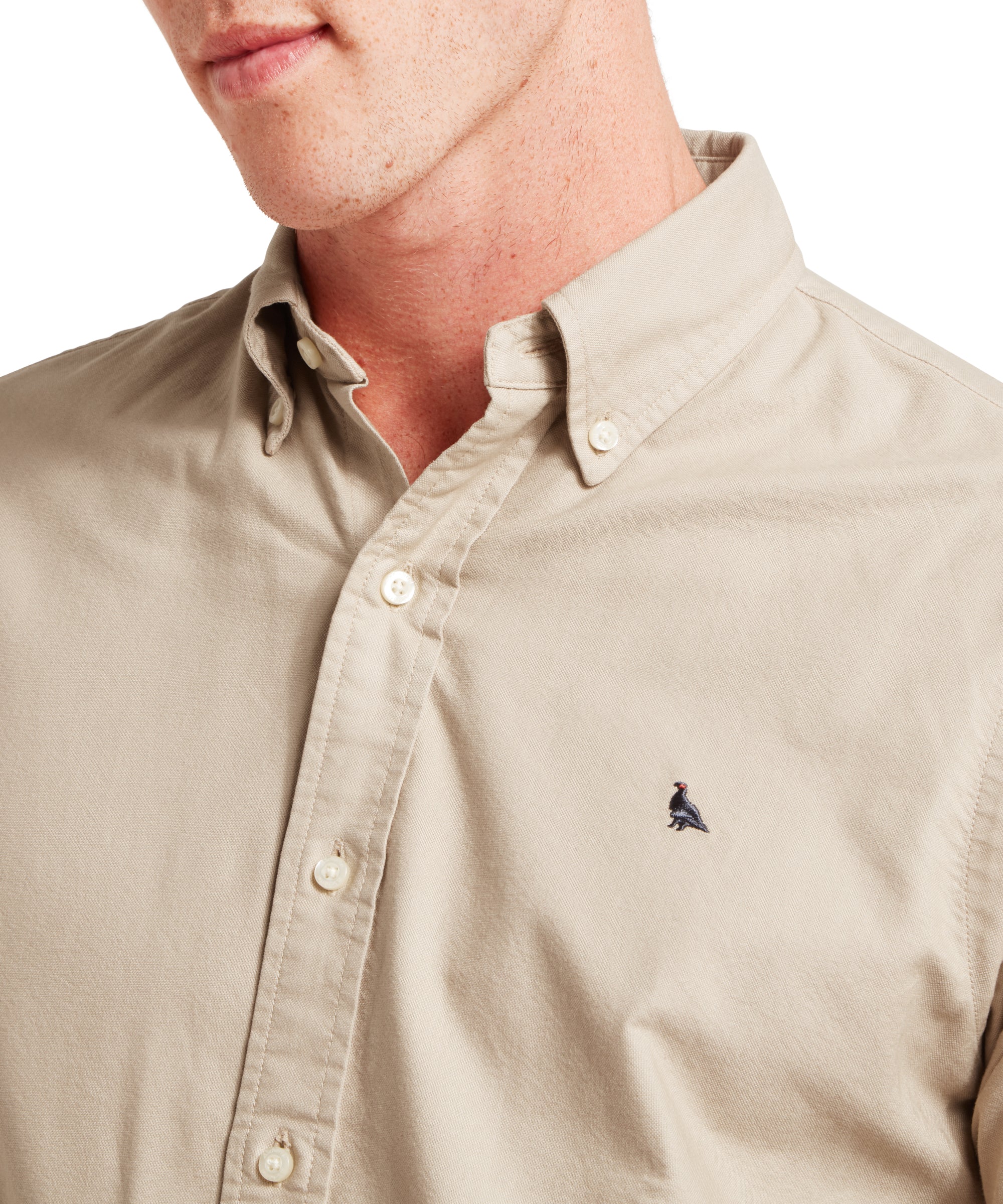 Beige button-up shirt with a small logo on a white background