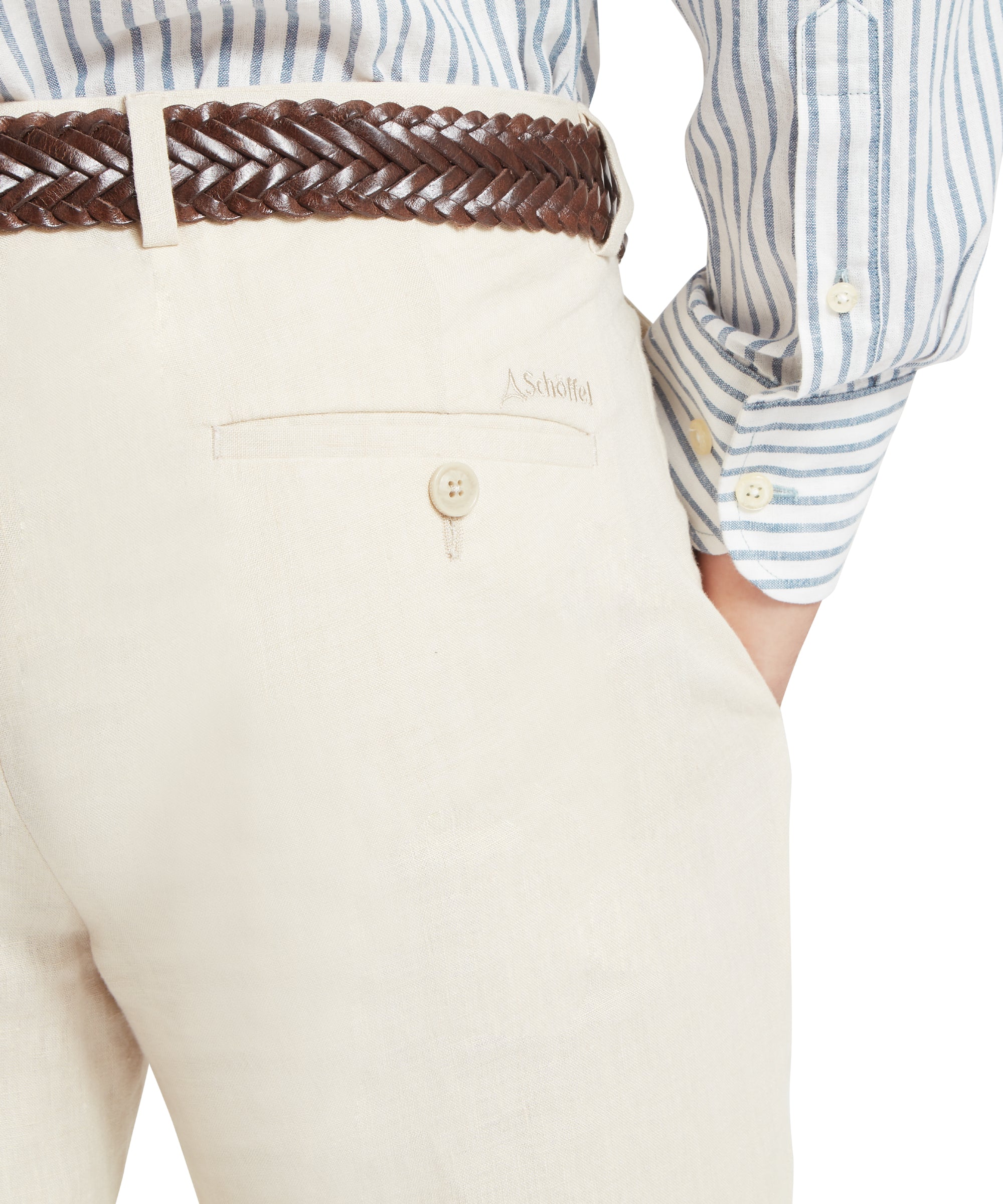 Close-up of cream linen trousers with a buttoned back pocket and “Schöffel” embroidered above. Paired with a brown braided belt and a blue-and-white vertically striped button-down shirt. Right hand placed in the front pocket.