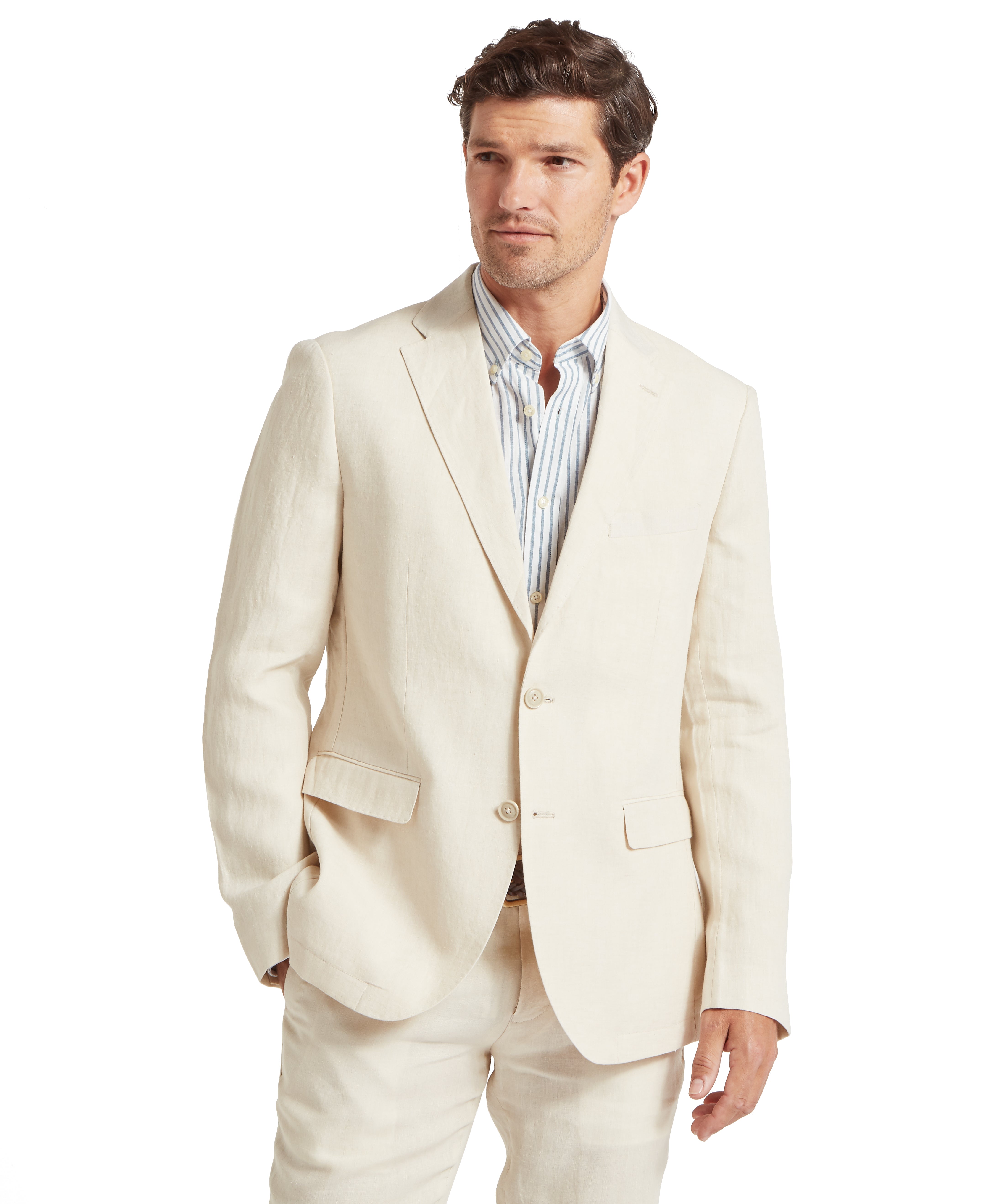Man wearing a light cream suit with a blue-and-white striped button-down shirt, standing against a white background with one hand in his pocket