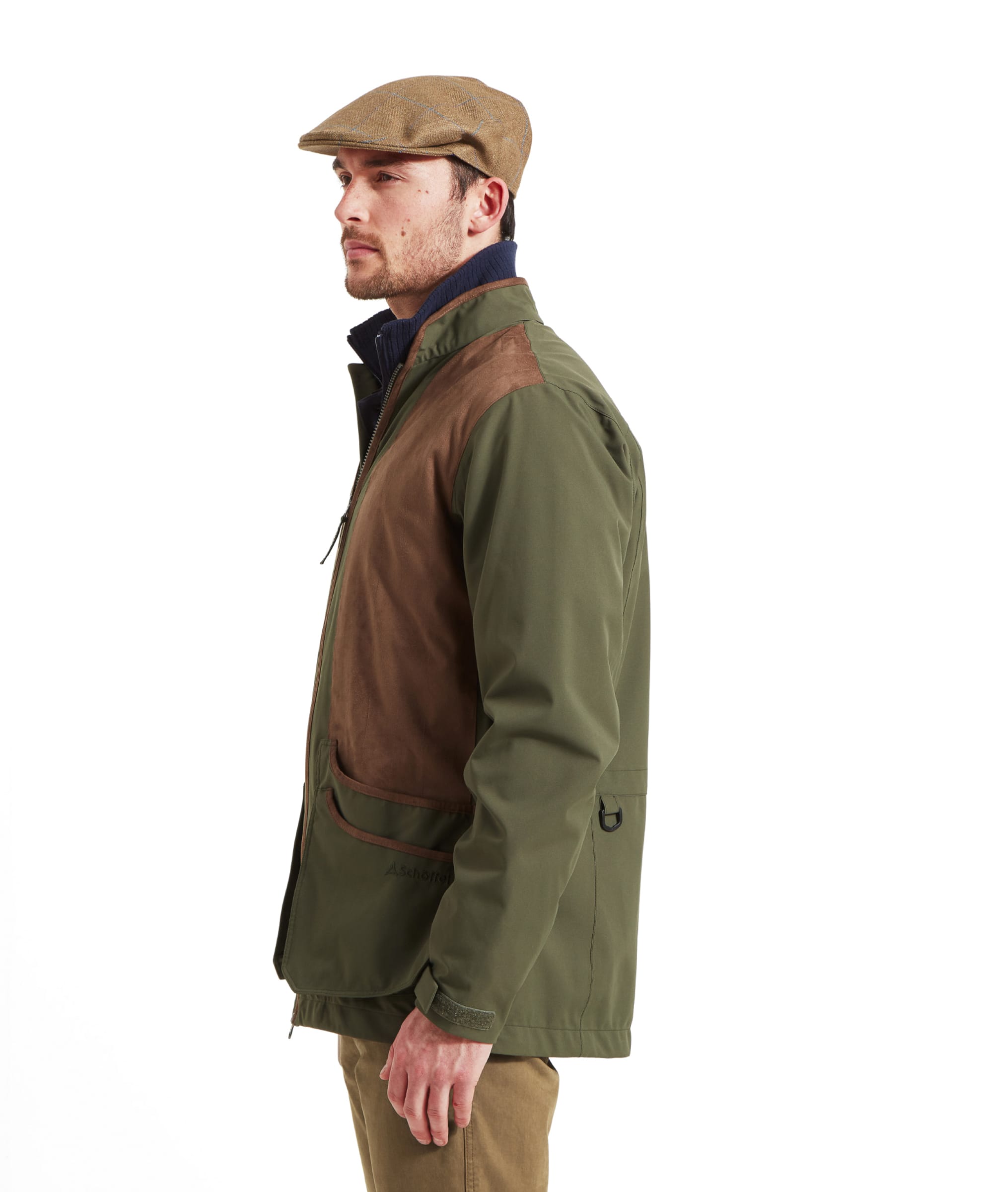 Schöffel Men's Grimsthorpe Clay Shooting Jacket in Green — side view showing contrast suede shooting patches, deep cartridge pockets with suede trim and a layered knitwear collar, styled with a tweed flat cap