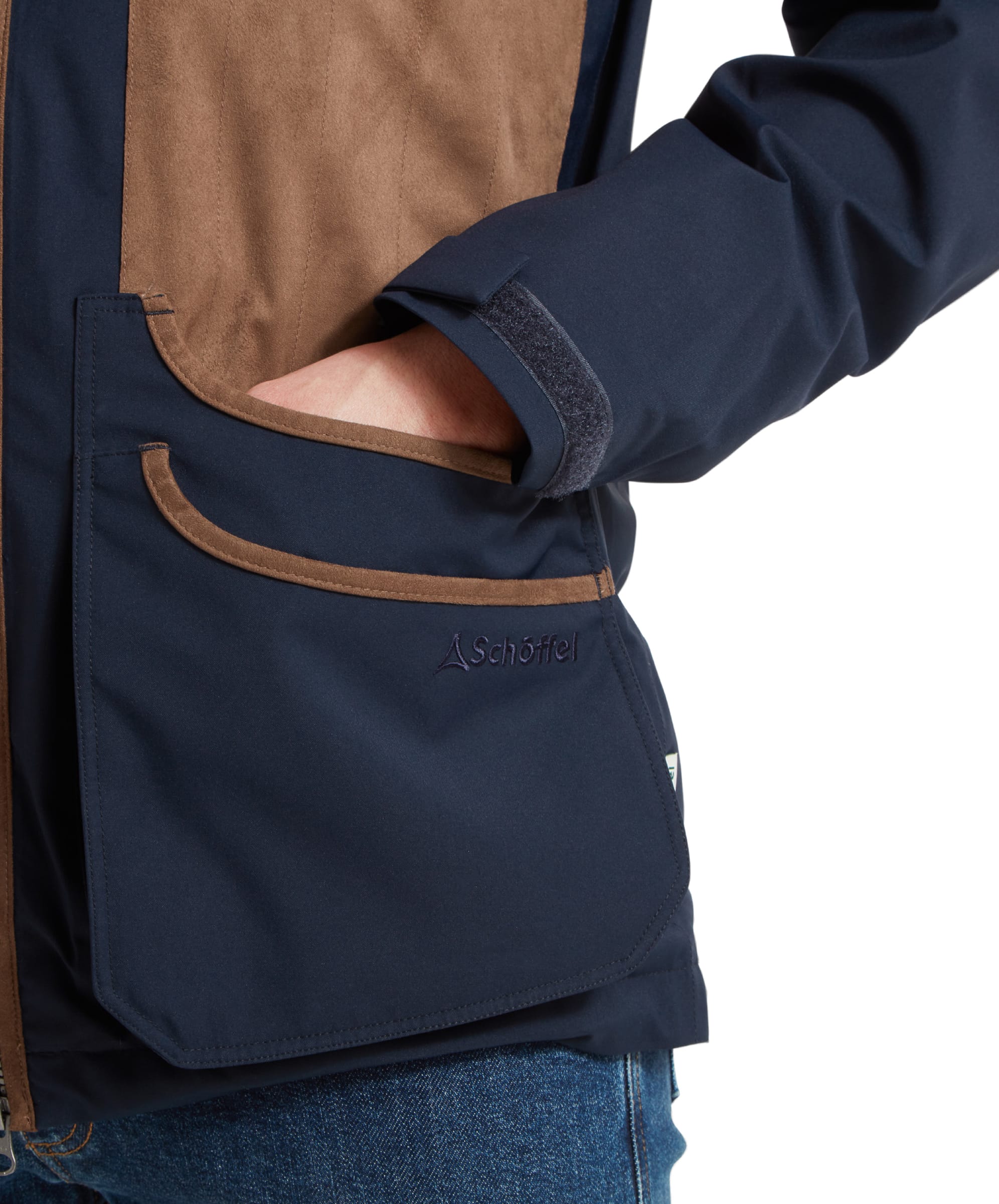 Schöffel Men's Grimsthorpe Clay Shooting Jacket in Blue — close-up of deep cartridge pocket with suede trim, Schöffel embroidered logo, hook-and-loop cuff adjuster and woven label detail