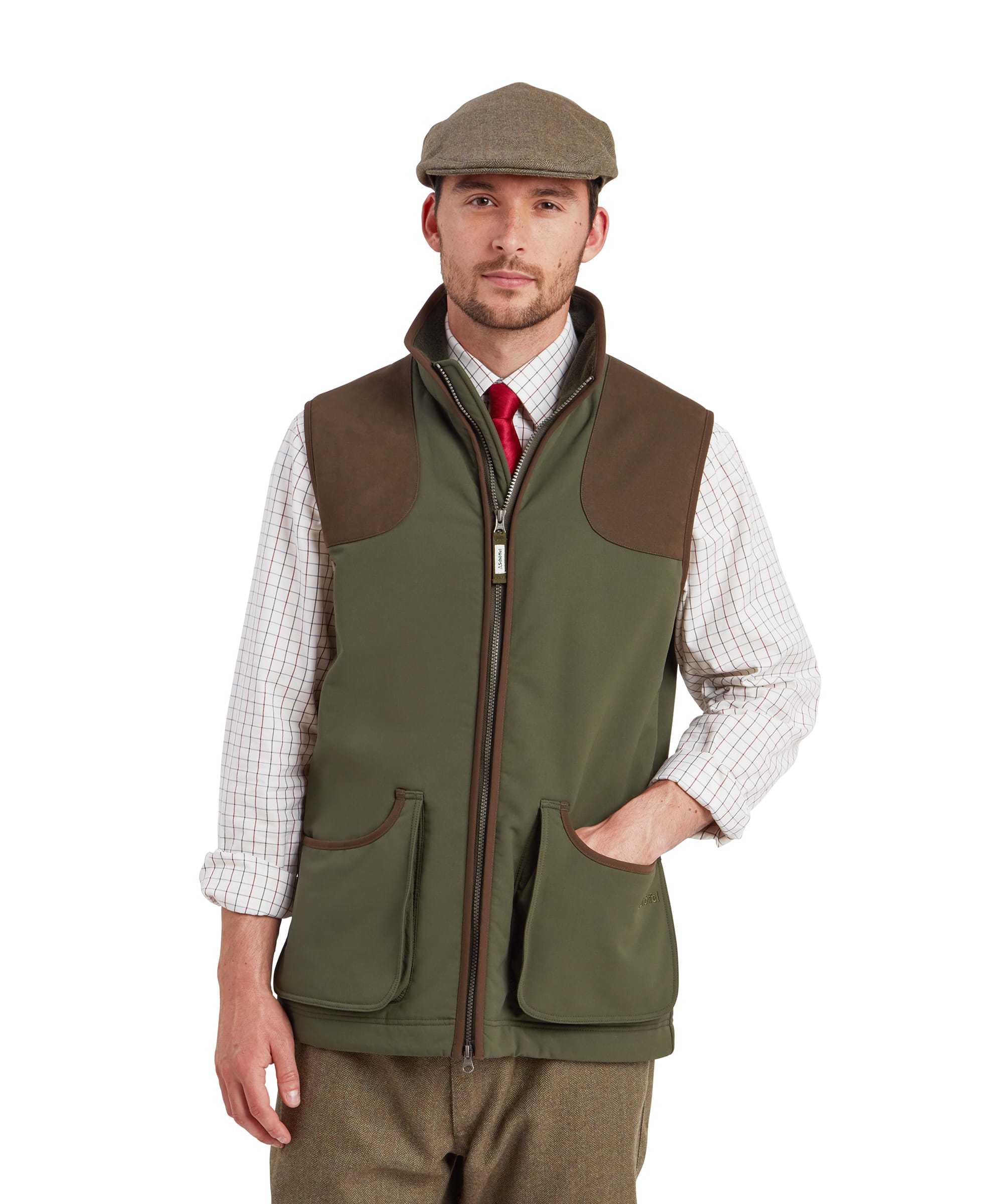 Schöffel Men's Gunby Gilet in Green — front view showing suede shoulder patches, full-length zip, lower pockets with suede trim and Schöffel branding, layered over a check shirt with tie, styled with tweed trousers