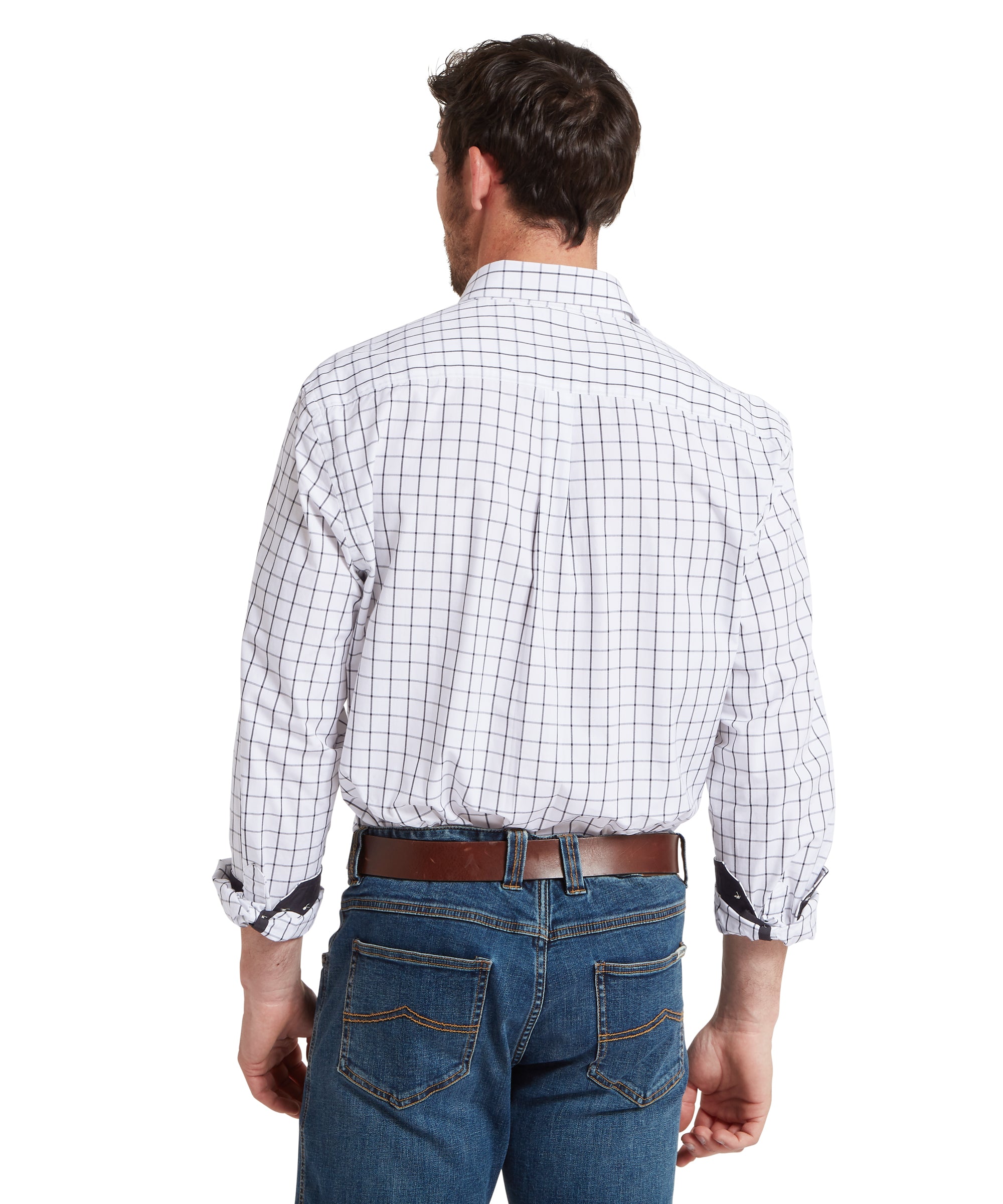 Back view of a man standing against a plain white background wearing a white long‑sleeve checked shirt with a grid pattern, tucked into blue jeans with a brown belt, with the sleeves rolled to the forearms.