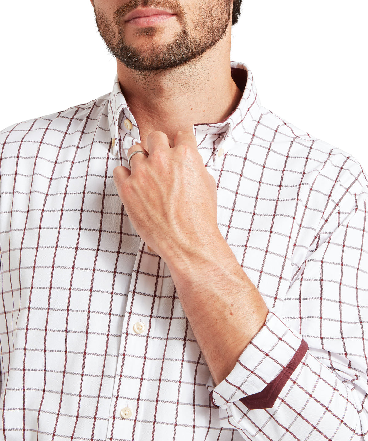 A close-up of a man wearing a white long-sleeve button-down shirt with a red windowpane pattern