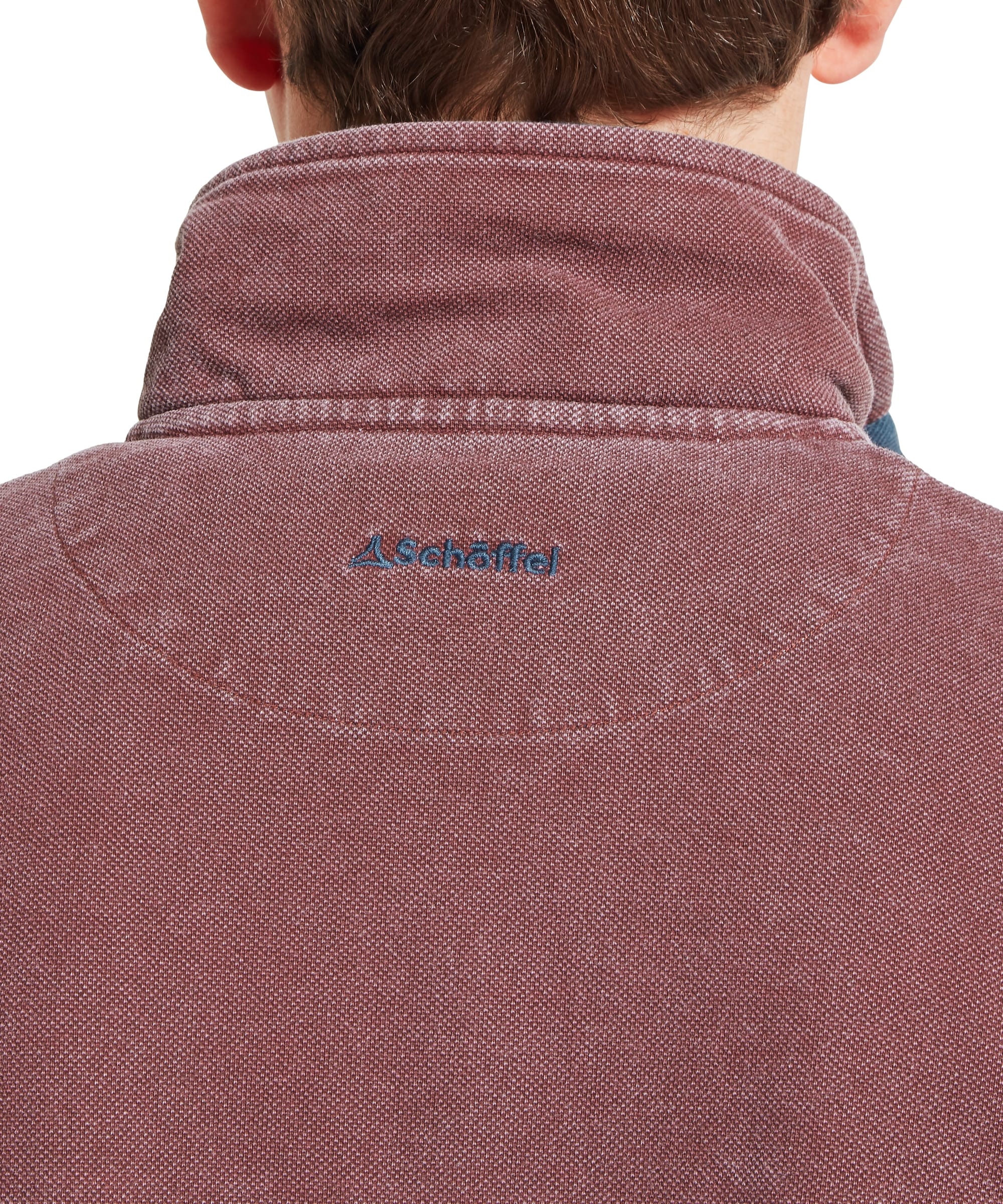 Close-up detail of Schöffel Men's Helford Heritage Sweatshirt in red showing quarter-zip collar, woven chest placket, and embroidered pheasant logo on pigment-dyed cotton