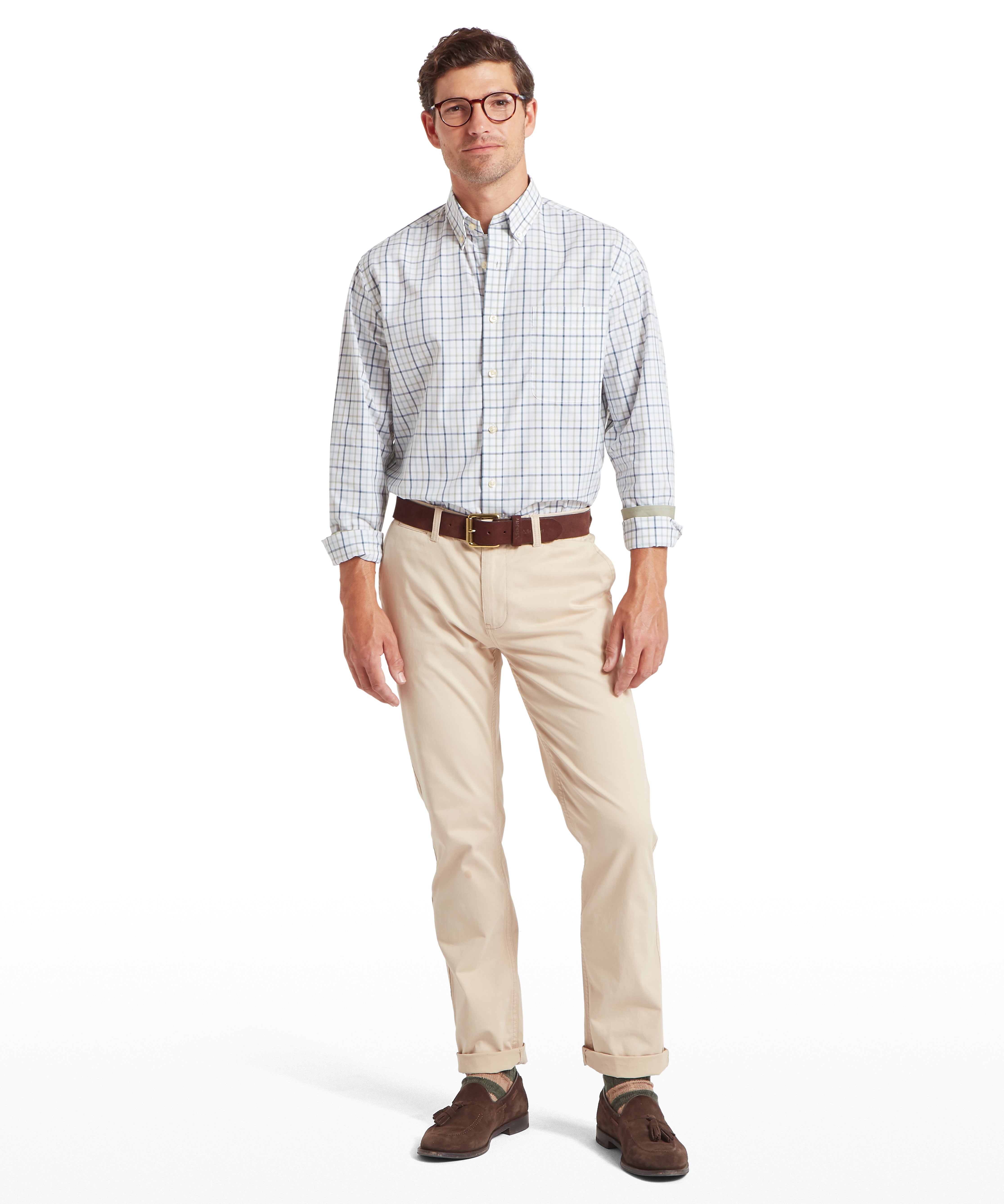 Man wearing a checked shirt, beige chinos, and brown shoes on a white background