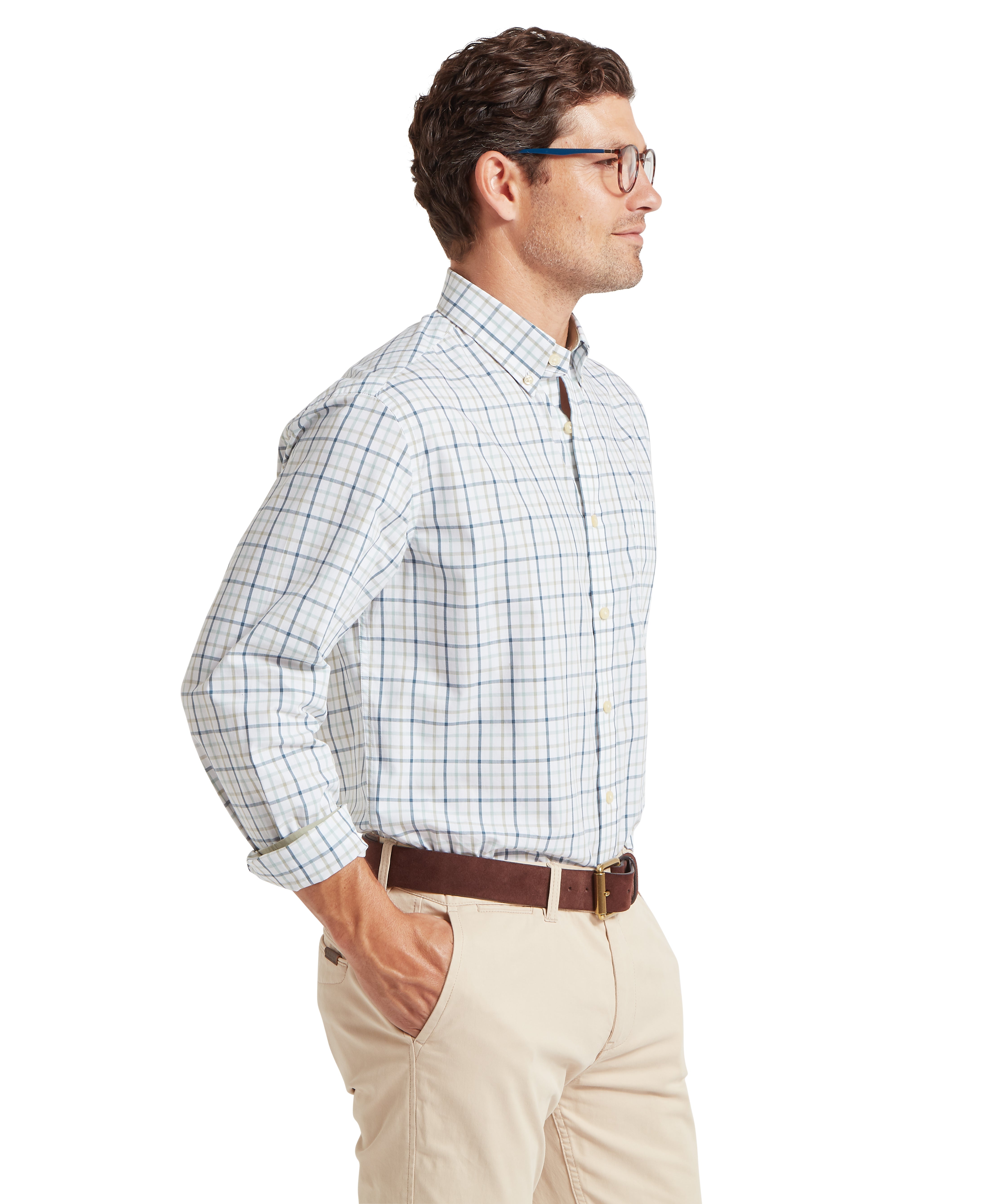 Man standing sideways wearing a checked shirt and beige trousers on a white background