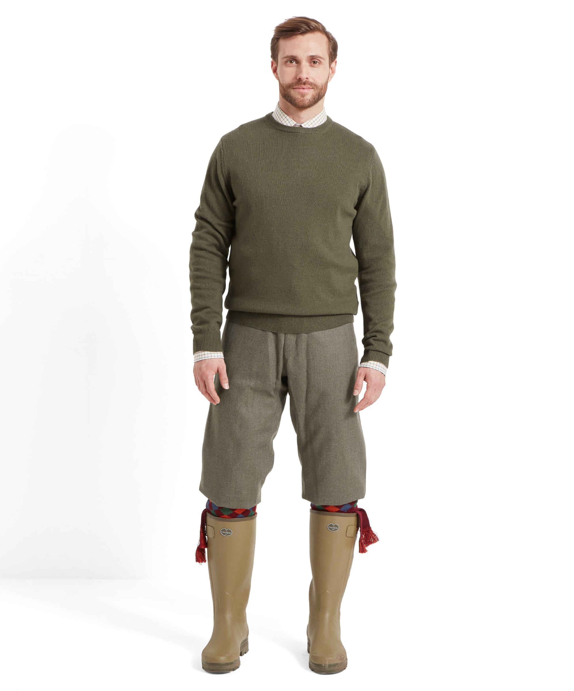 Man wearing a green jumper, green tweed trousers, and green wellington boots on a white background