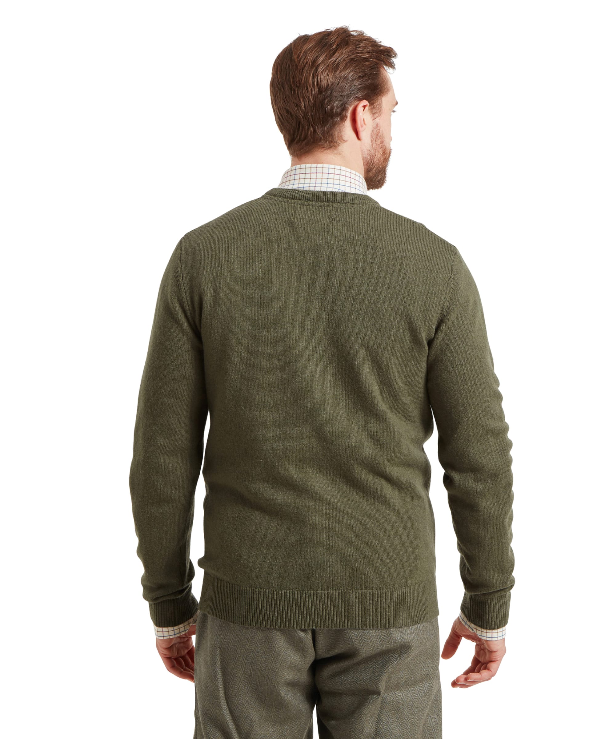 Back view of a man standing against a plain white background, wearing a green knitted jumper over a checked shirt, paired with green tweed trousers.