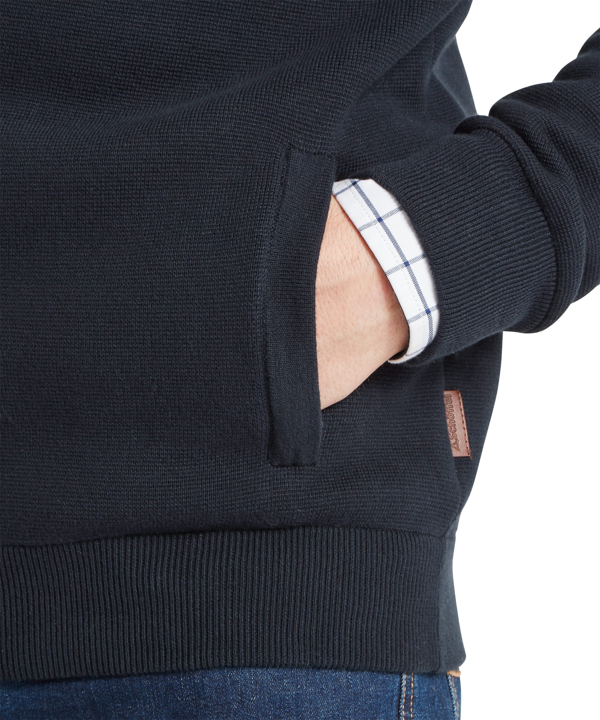 Close-up detail of Schoffel Mens Marlow Full-Zip Jumper in navy showing side seam pocket, ribbed hem and Schoffel leather woven label tab, with check shirt cuff visible