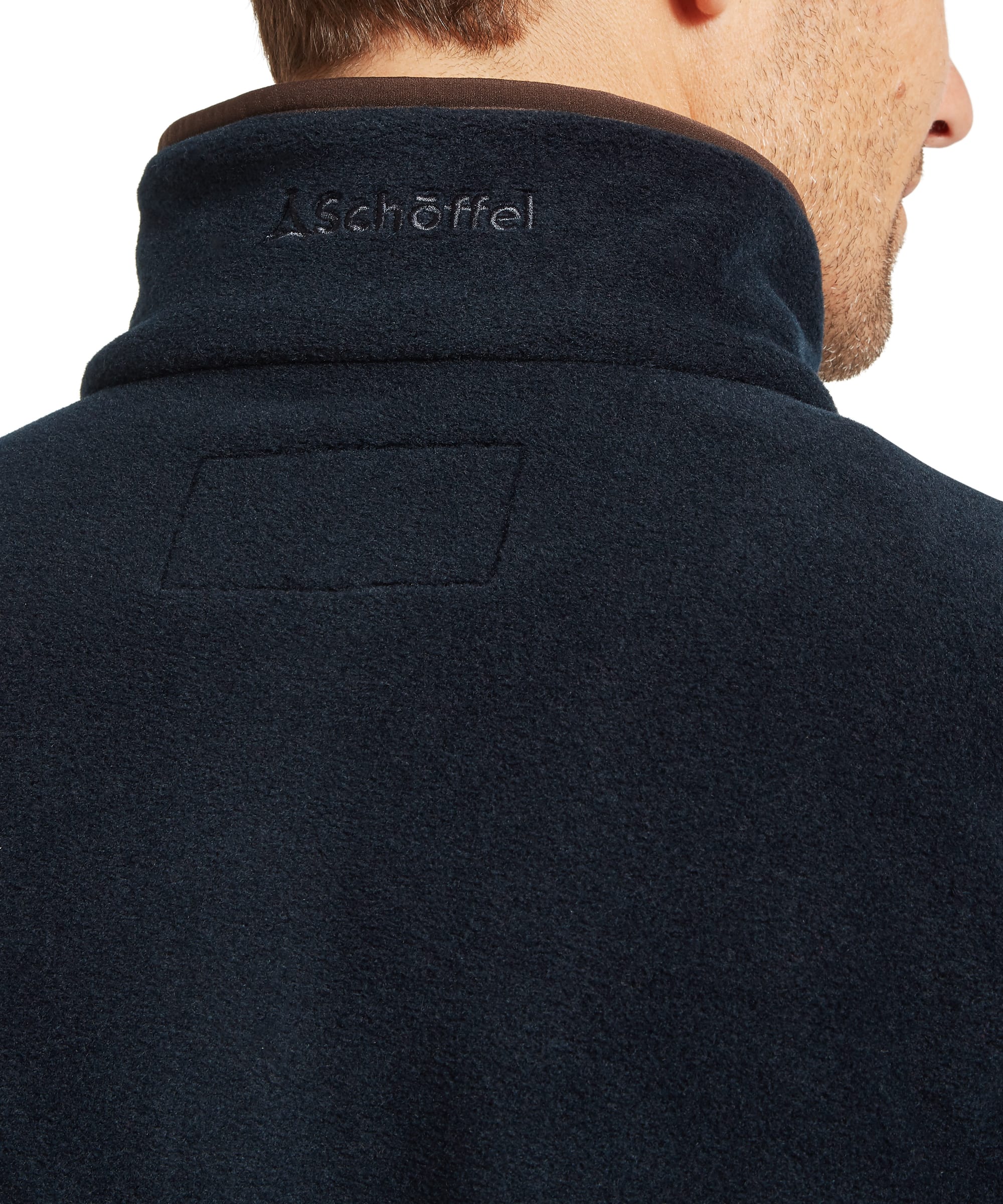 Close-up back neck detail of Schoffel Mens Norton Fleece in navy showing tone-on-tone Schoffel logo embroidery on fleece stand collar with contrast dark brown binding trim